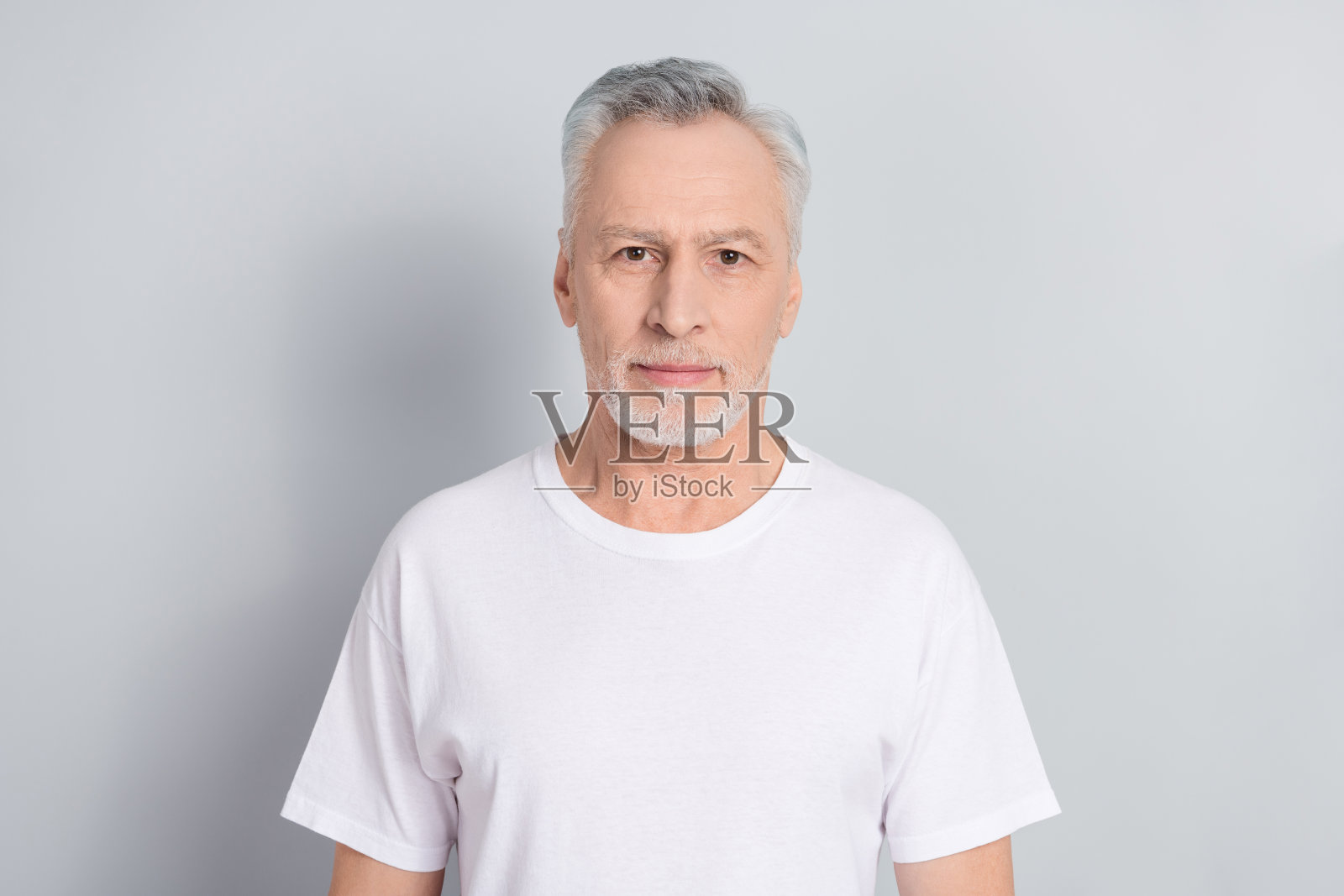 穿着白色T恤的搞笑老年男子，背景为灰色。照片摄影图片