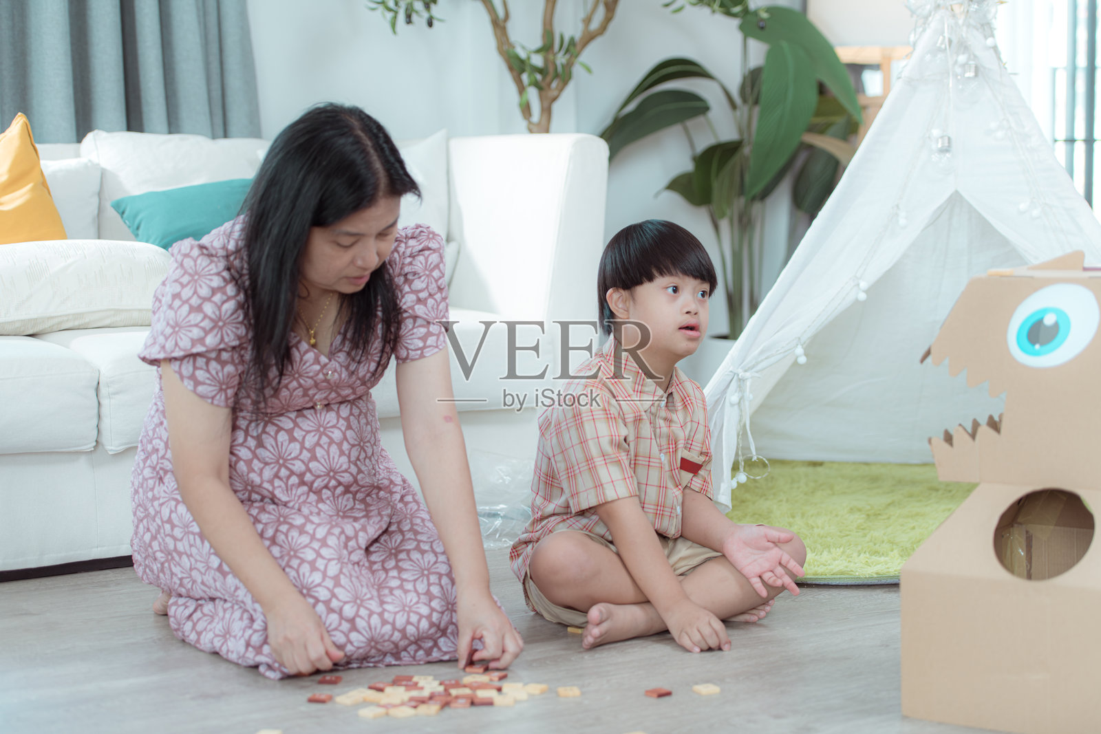 一个特殊的孩子和他的妈妈在家里的客厅里一起享受假期，放松和玩乐。照片摄影图片