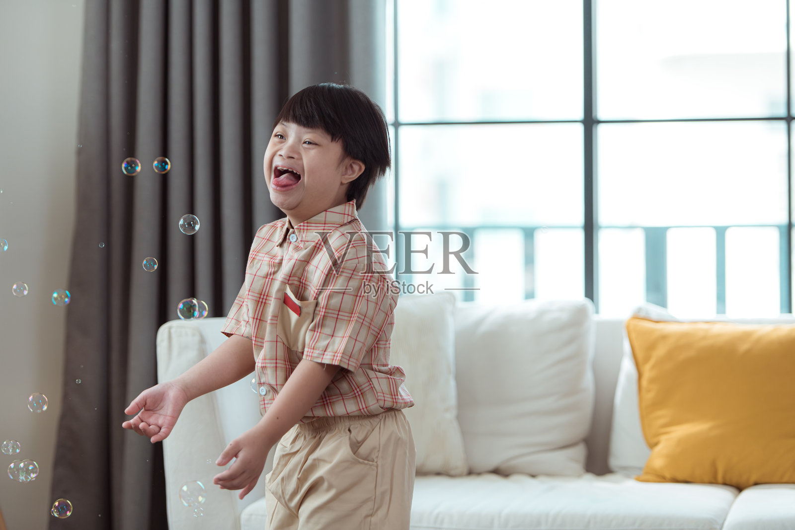 一个特殊的孩子在家里的客厅里玩泡泡袋，玩得很开心。照片摄影图片