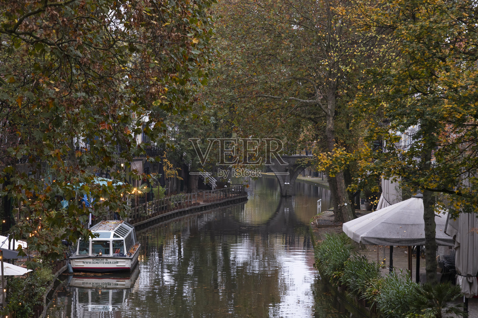在乌特勒支市中心的运河旁，一艘游船傍晚停靠在带露台的餐厅。照片摄影图片