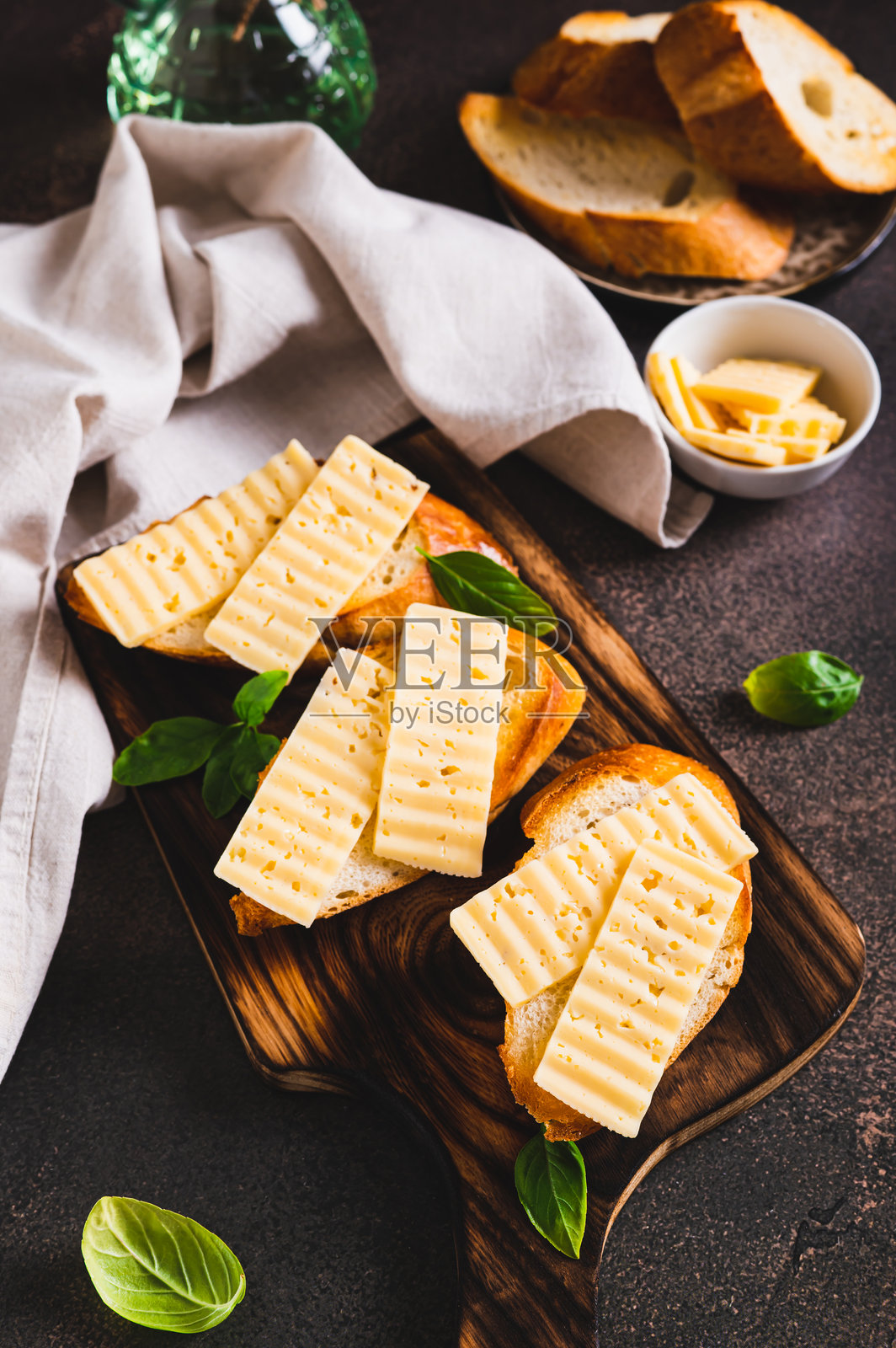 桌子上的切板上放着炸面包吐司，配有奶酪和罗勒，垂直视角。照片摄影图片
