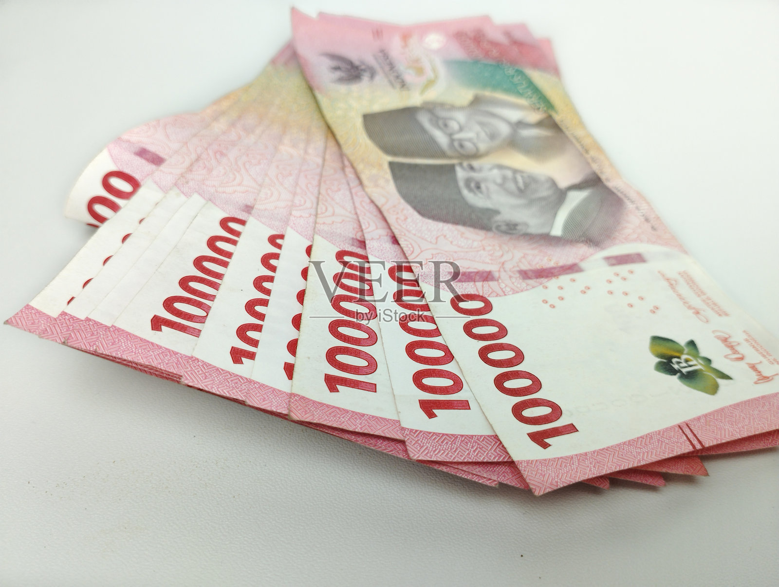 特写镜头：十万印尼钞票（卢比）。现金支付概念。印尼卢比货币（Rp. 100,000 十万卢比）在白色背景上。照片摄影图片