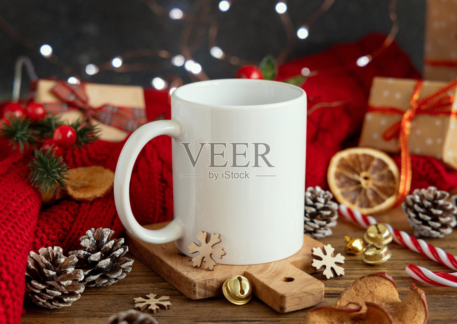 白色咖啡杯旁边是红色针织毛衣和圣诞装饰及灯光，冬季样板图照片摄影图片