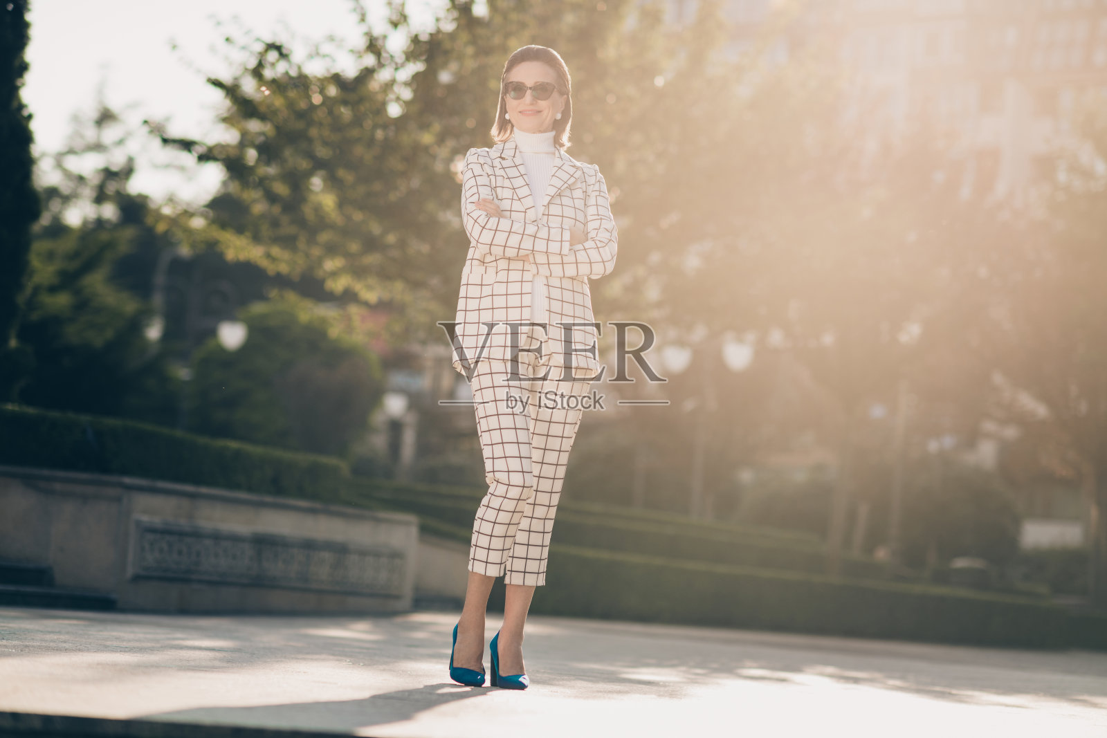 优雅的年长女士在户外摆姿势，双臂交叉，穿着格子服装的全身照片照片摄影图片