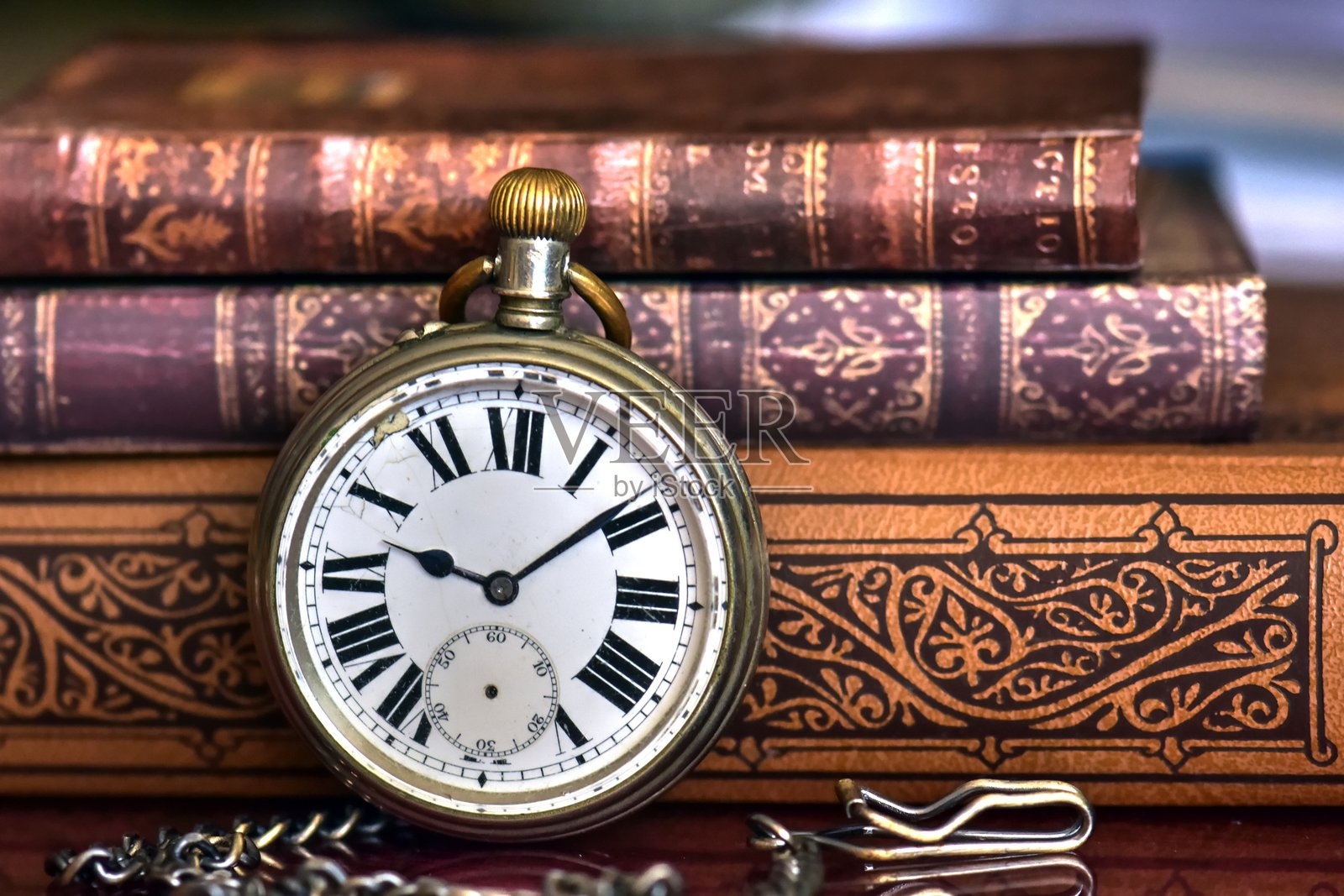 桌子上叠放的书籍与怀表的特写镜头照片摄影图片