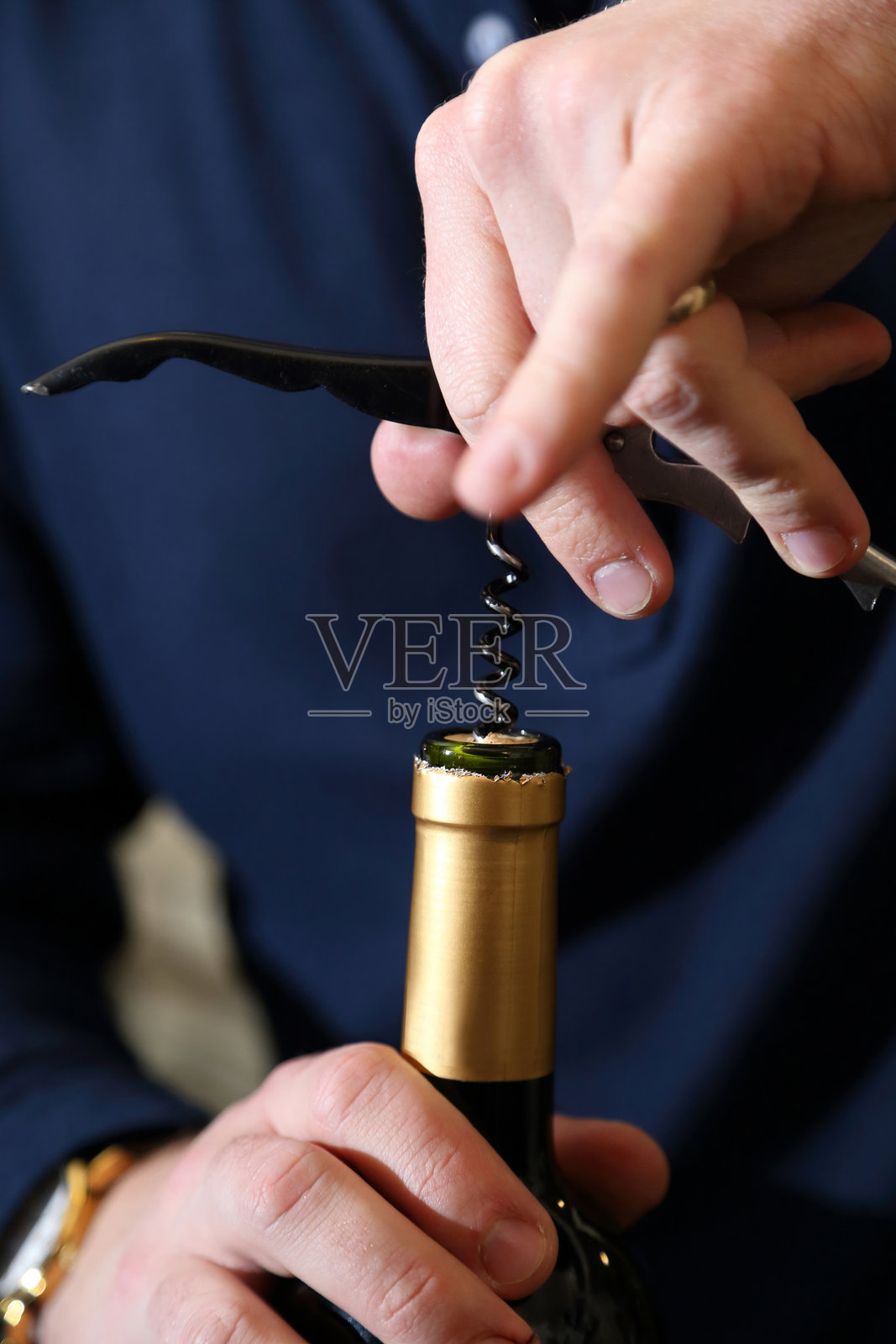 红酒用侍酒师刀开瓶。特写手部、瓶塞和瓶颈。酒瓶用侍酒师刀打开。照片摄影图片