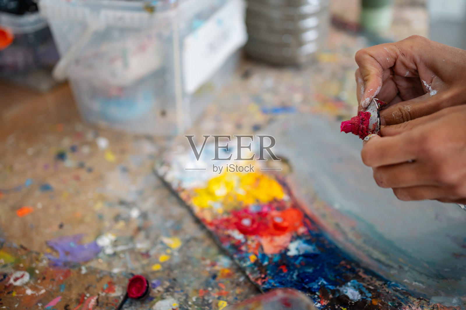 艺术家在艺术工作室的木桌上挤压油漆管照片摄影图片