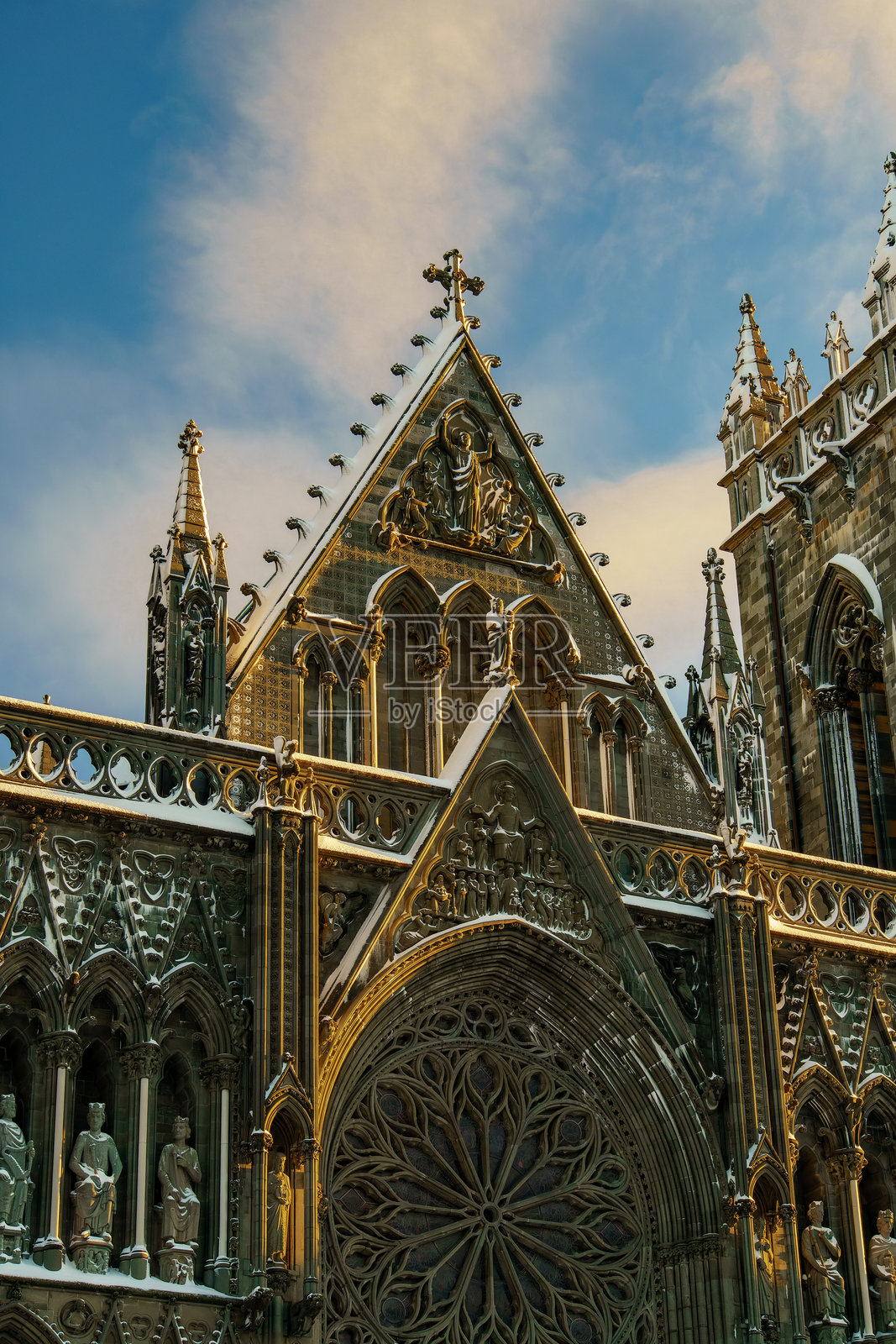 挪威特隆赫姆的尼达罗斯大教堂外立面上的日落，雕像映衬其中。尼达罗斯大教堂，耶稣被钉在十字架上。照片摄影图片