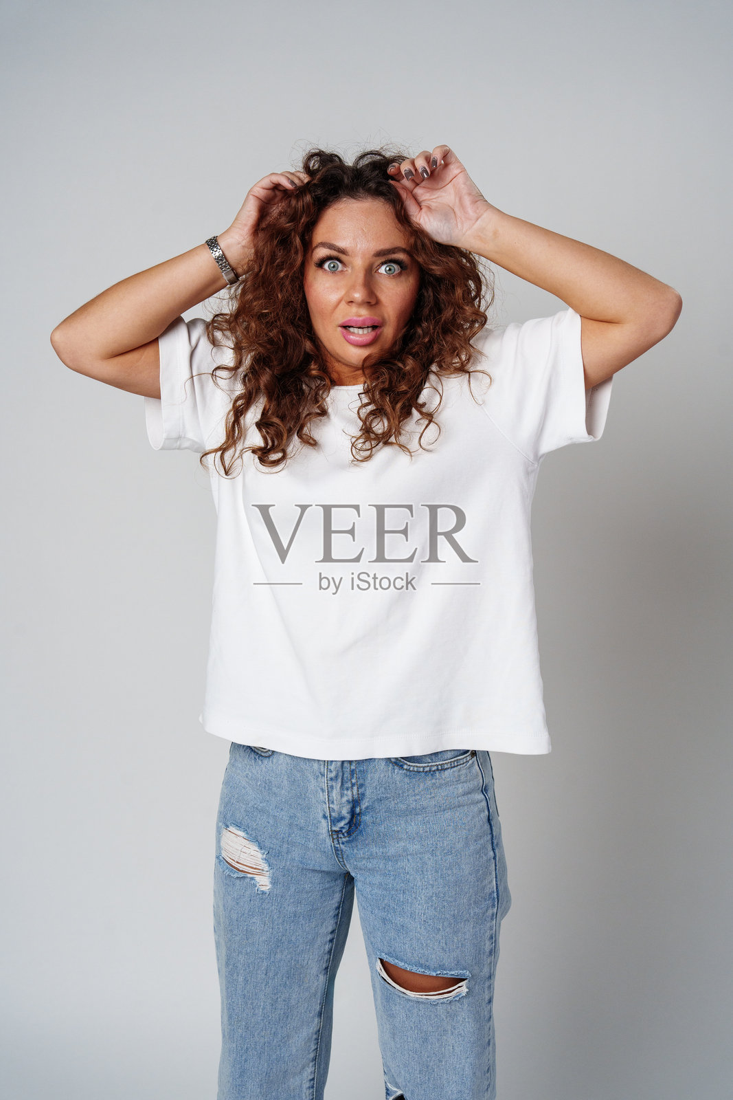 惊讶的女性在工作室环境中用睁大的眼睛和举起的双手表达强烈的情感照片摄影图片