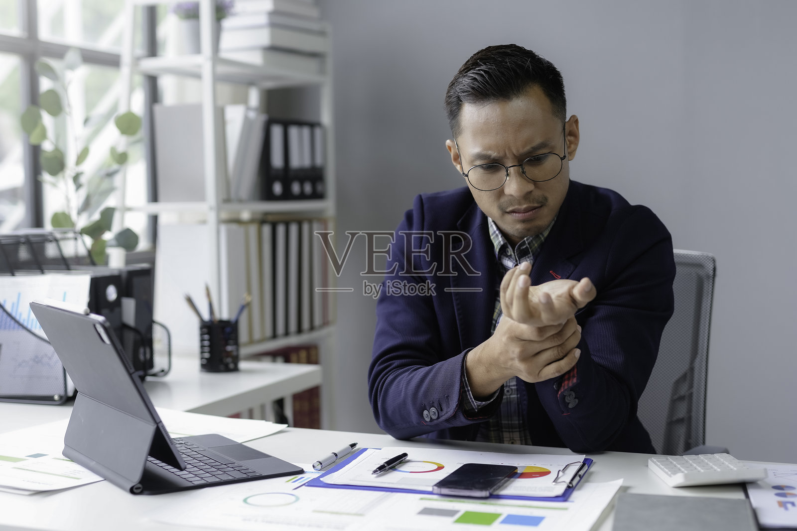 亚洲商人因长时间使用电脑而感到手腕疼痛，这是一种常见的健康问题。照片摄影图片