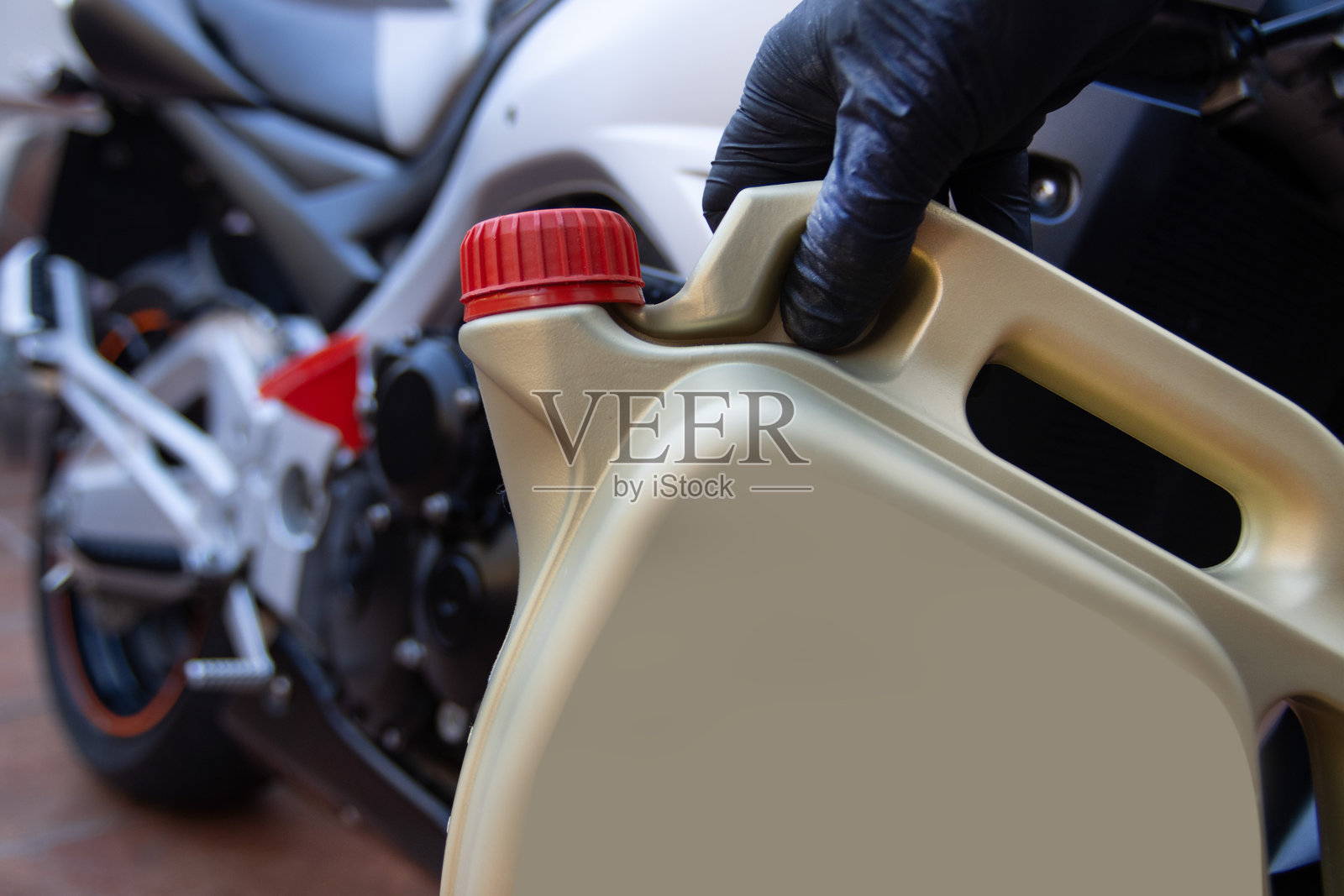 一罐摩托车用机油。金色，带红色瓶盖。背景中有一辆摩托车。照片摄影图片