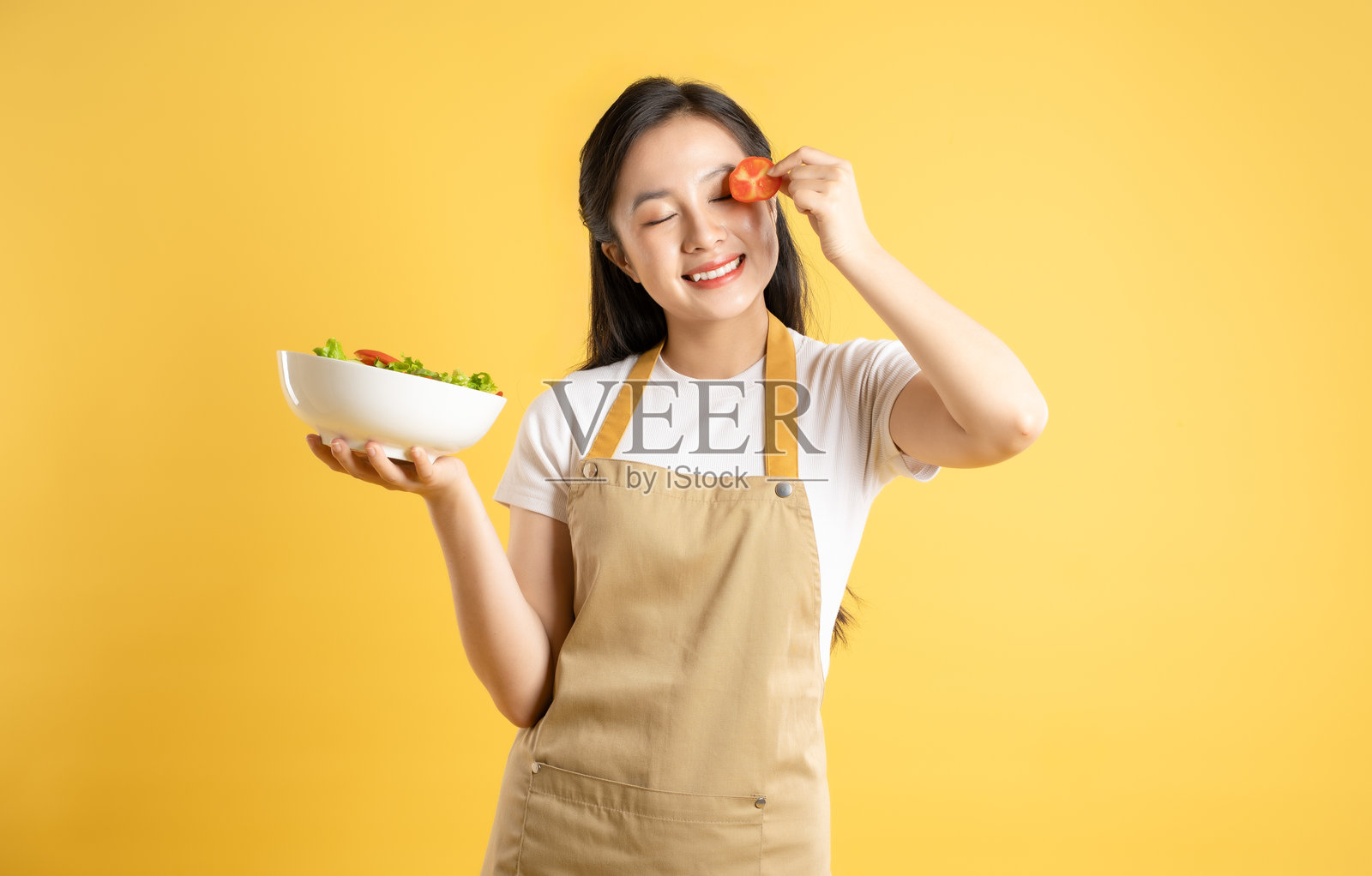 亚洲家庭主妇女孩在黄色背景下摆姿势的肖像照片摄影图片