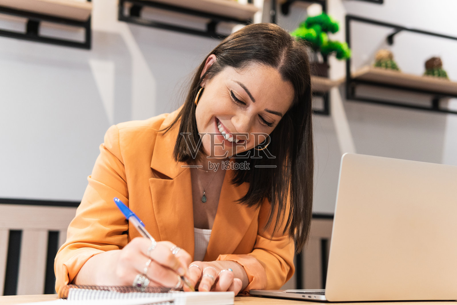 微笑的女性在咖啡馆工作时在笔记本上做笔记照片摄影图片