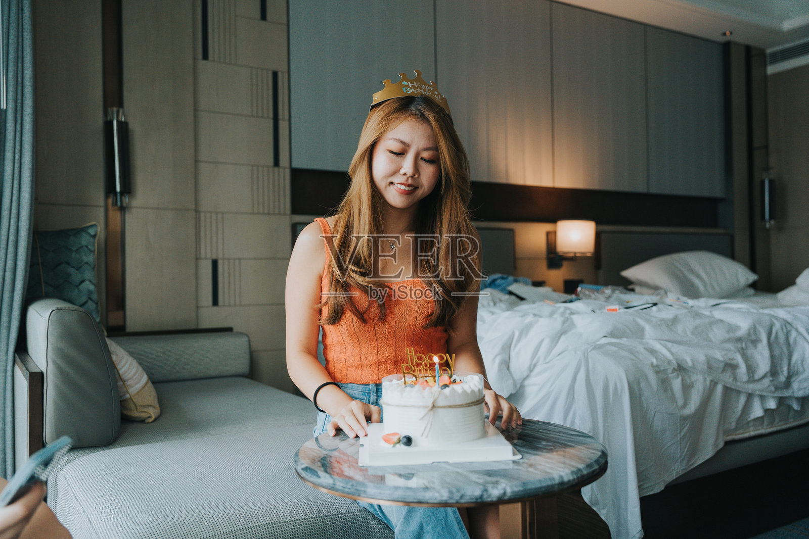 快乐的Z世代女孩们在中国大湾区的珠海旅行。她们在酒店房间里与朋友庆祝生日，面前摆着一个生日蛋糕。照片摄影图片