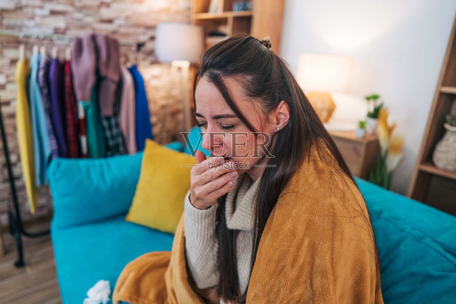 一位36岁的生病女性坐在客厅的沙发上。照片摄影图片