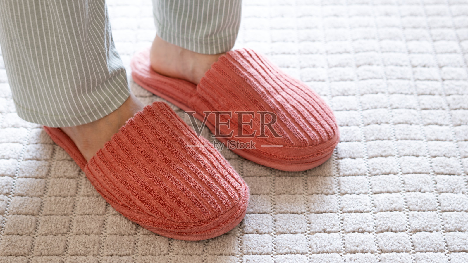 客厅里柔软的白色地毯上的拖鞋。留有文字空间。照片摄影图片