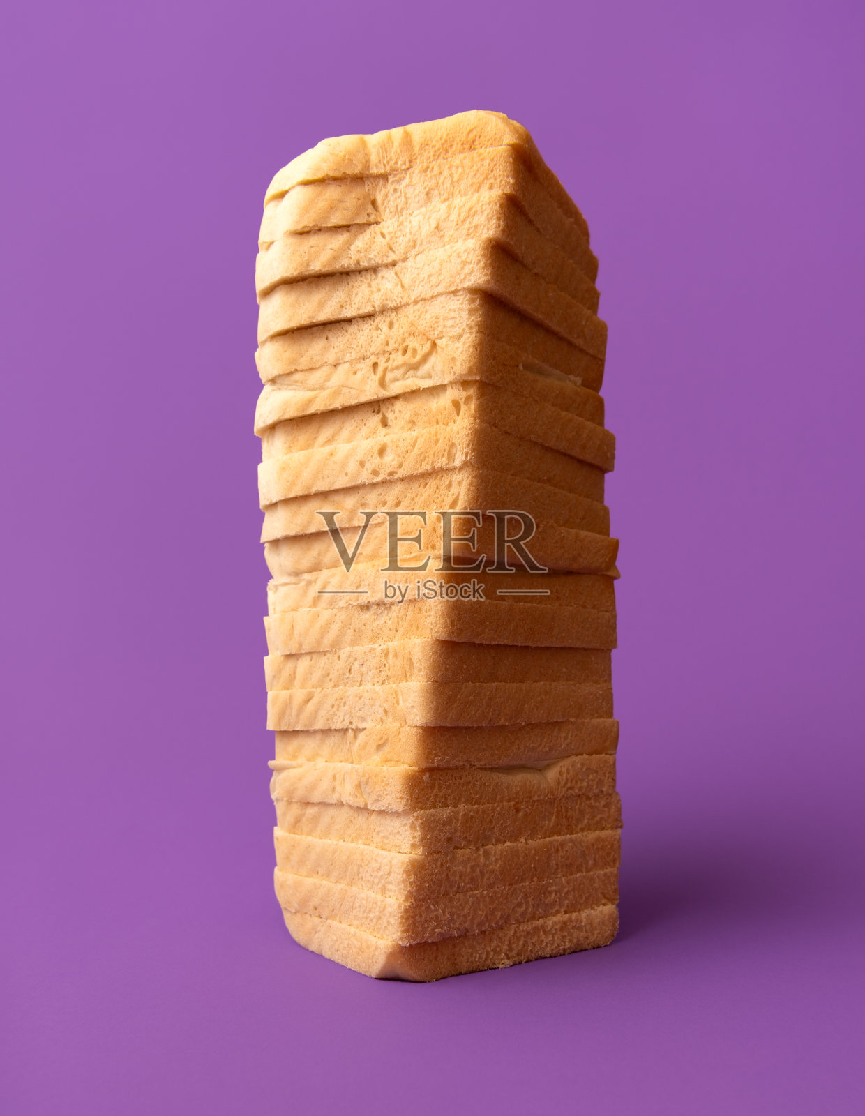 柔软的吐司面包，切片叠放在紫色桌子上，低角度视图照片摄影图片