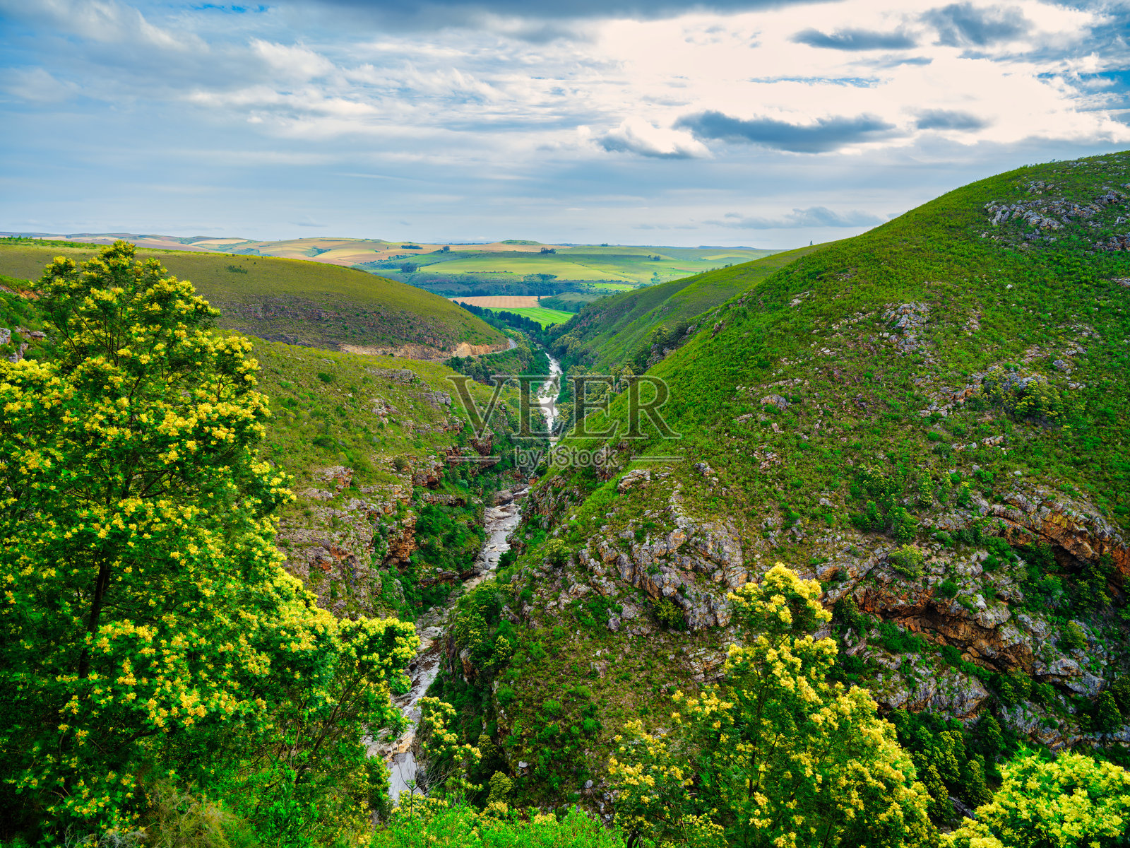 在蓝天白云的下午，特拉多河流经朗格堡山脉峡谷，位于南非西开普省的苏尔布拉克。照片摄影图片