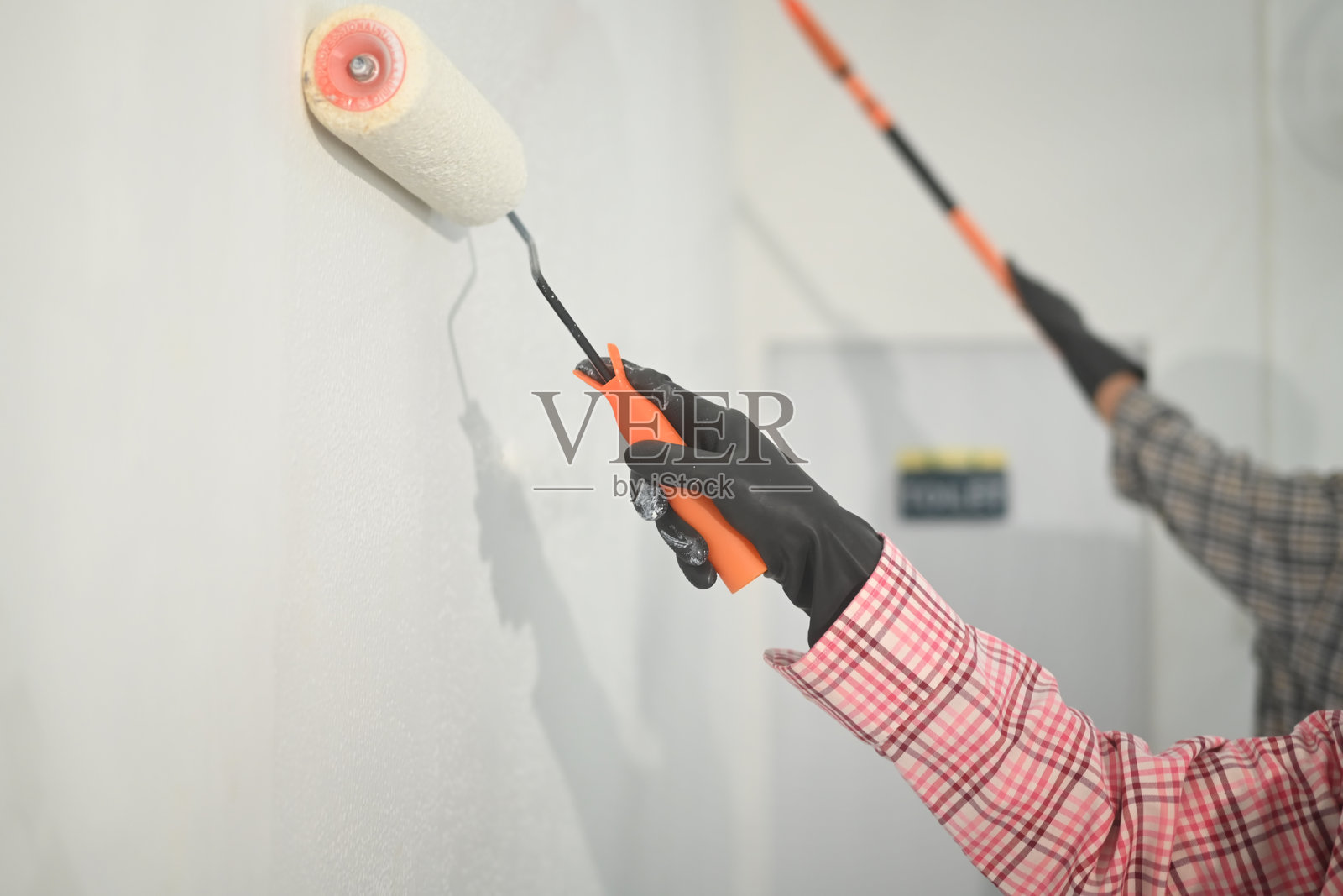 特写镜头，双手使用滚筒刷涂刷墙壁照片摄影图片