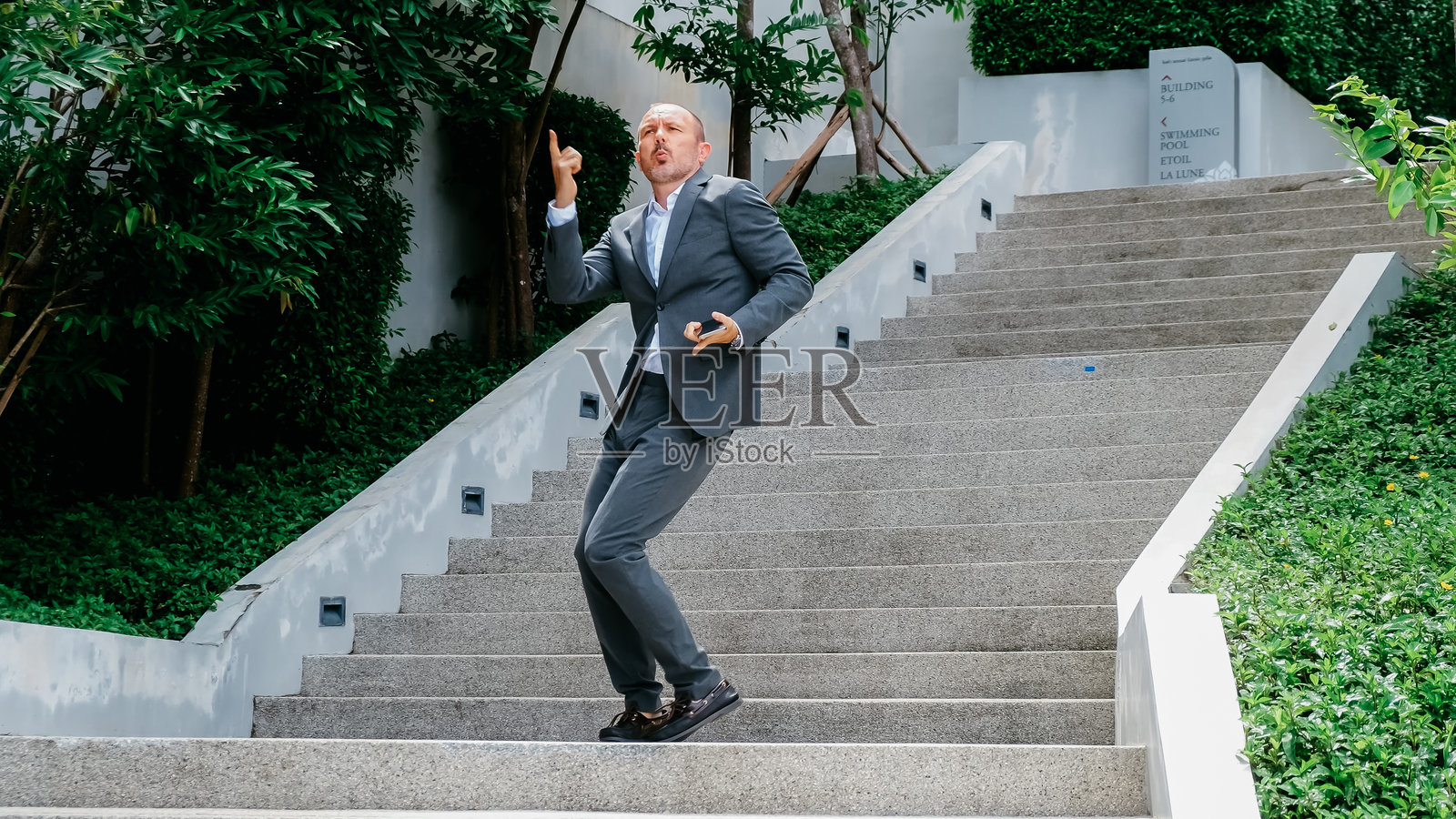 一位商人在现代办公室附近收到交易完成的好消息，开心地跳舞。成功和快乐情绪的概念。照片摄影图片