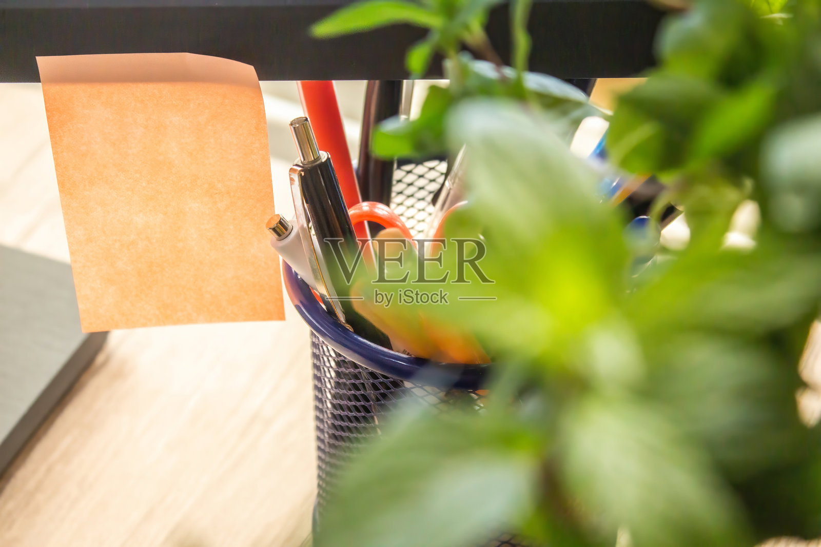 显示器上挂着一个空白的贴纸用于书写，附近放着一些笔和铅笔，适合办公室主题的文字背景。照片摄影图片