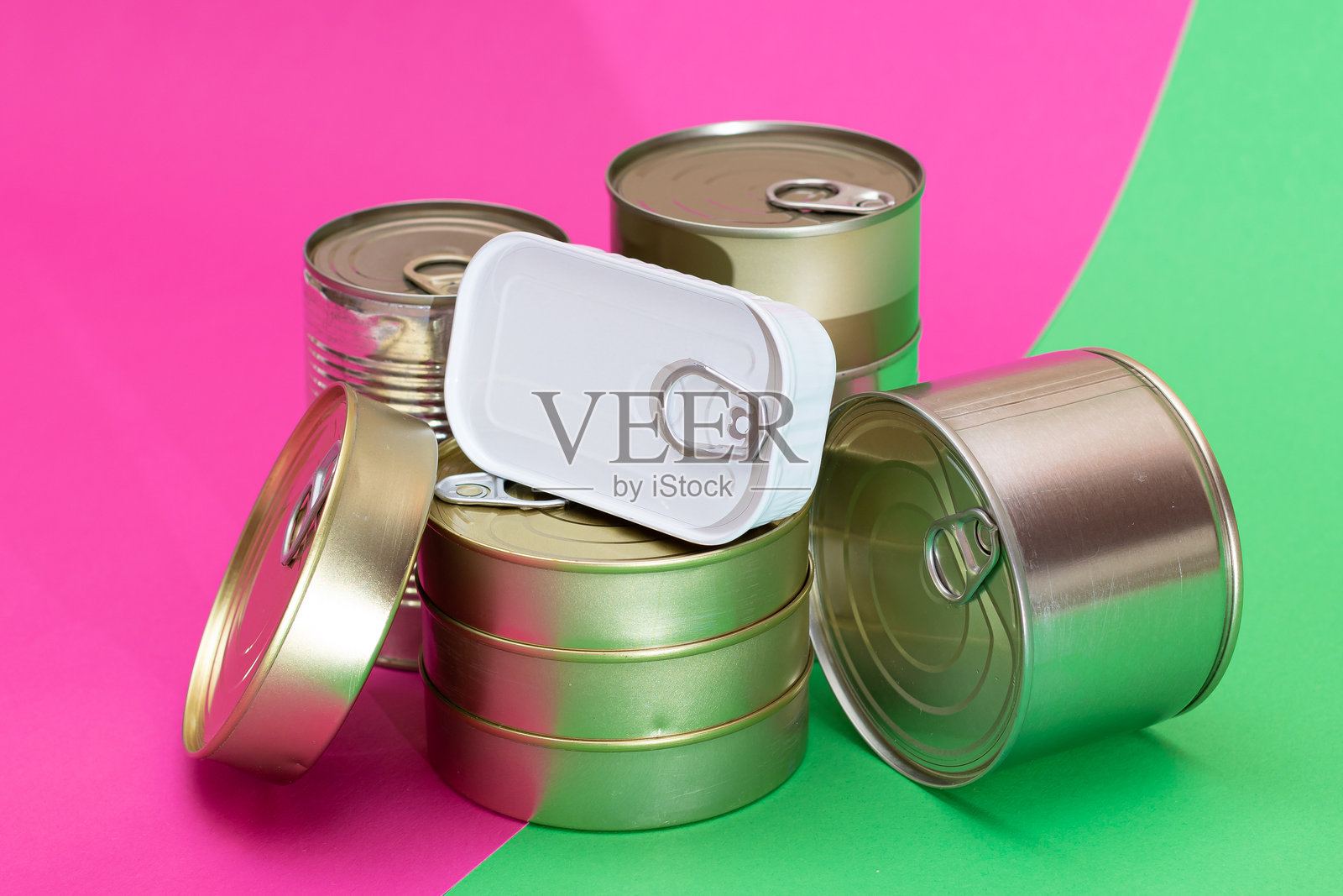 一组叠放的锡罐置于分割的绿色和青色背景上照片摄影图片