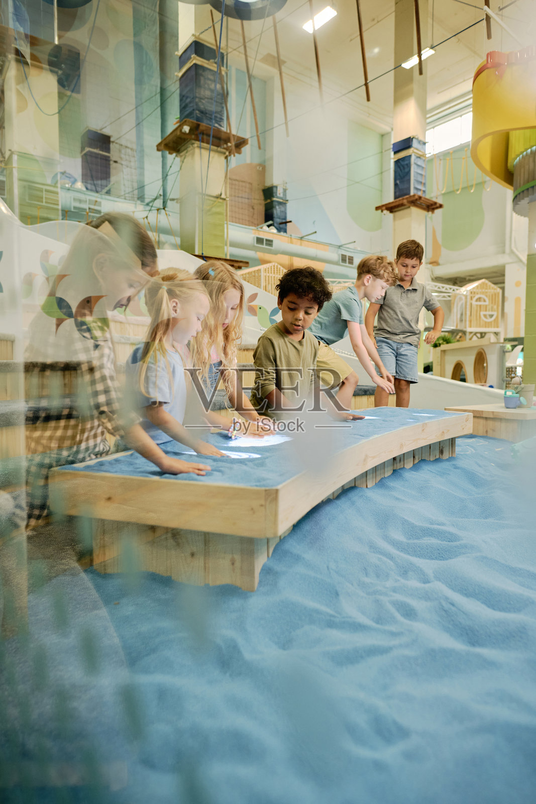 孩子们在桌子上用蓝色沙子画画照片摄影图片