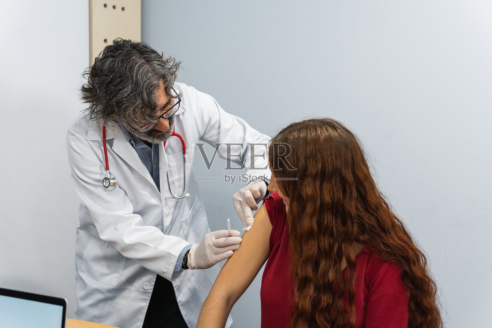 资深医生在患者注射后为其手臂贴上创可贴照片摄影图片