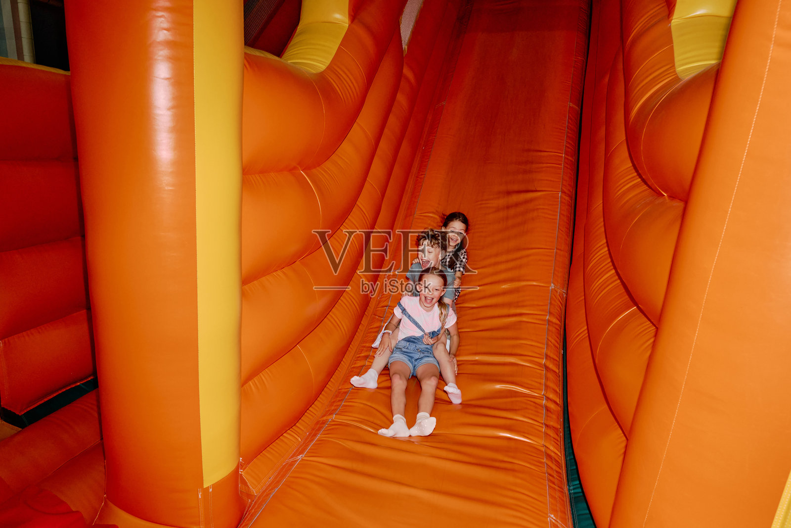 在柔软的滑梯上欢笑着滚下来照片摄影图片