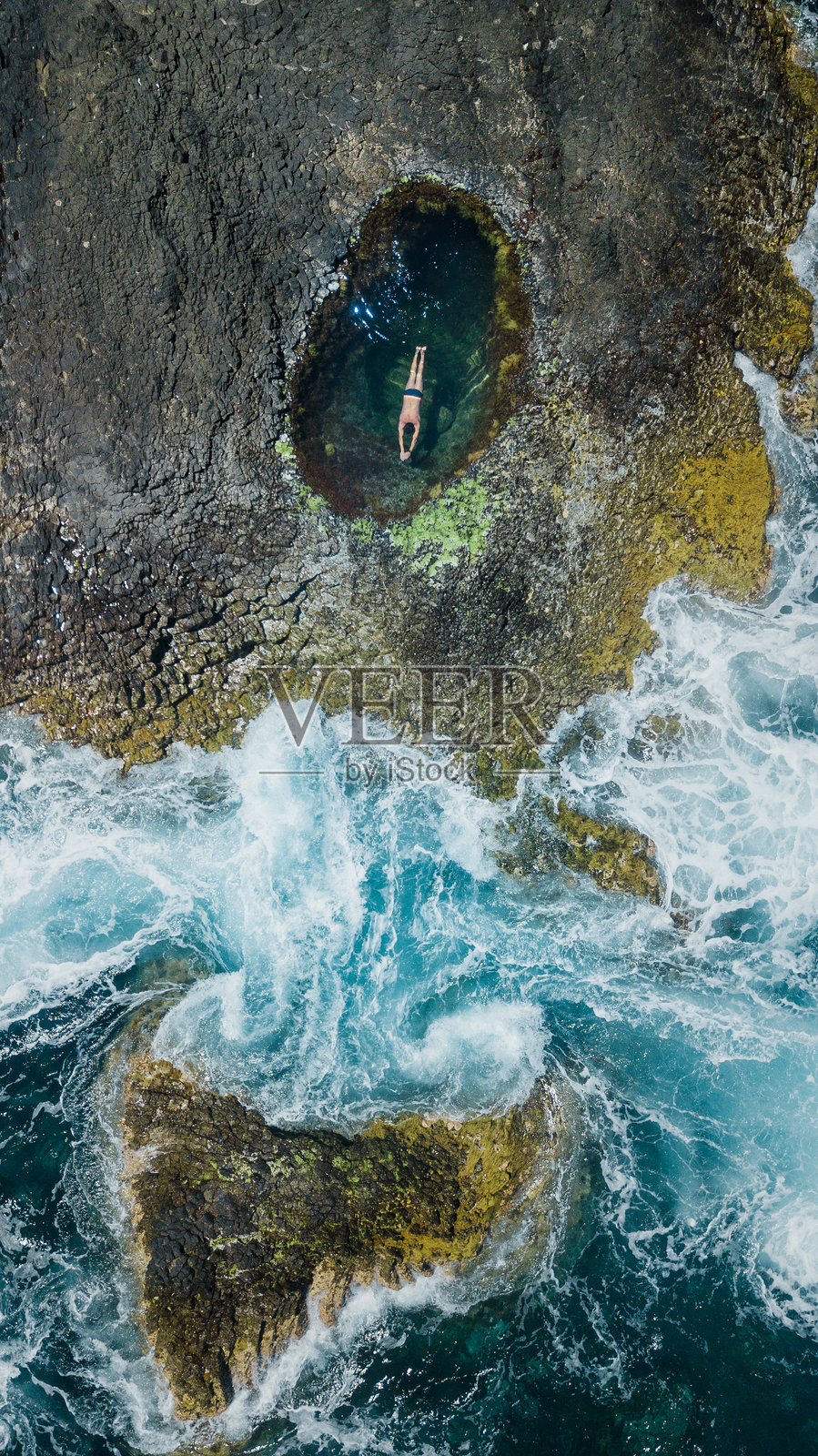 无人机视角下的男子在潮汐池中游泳照片摄影图片