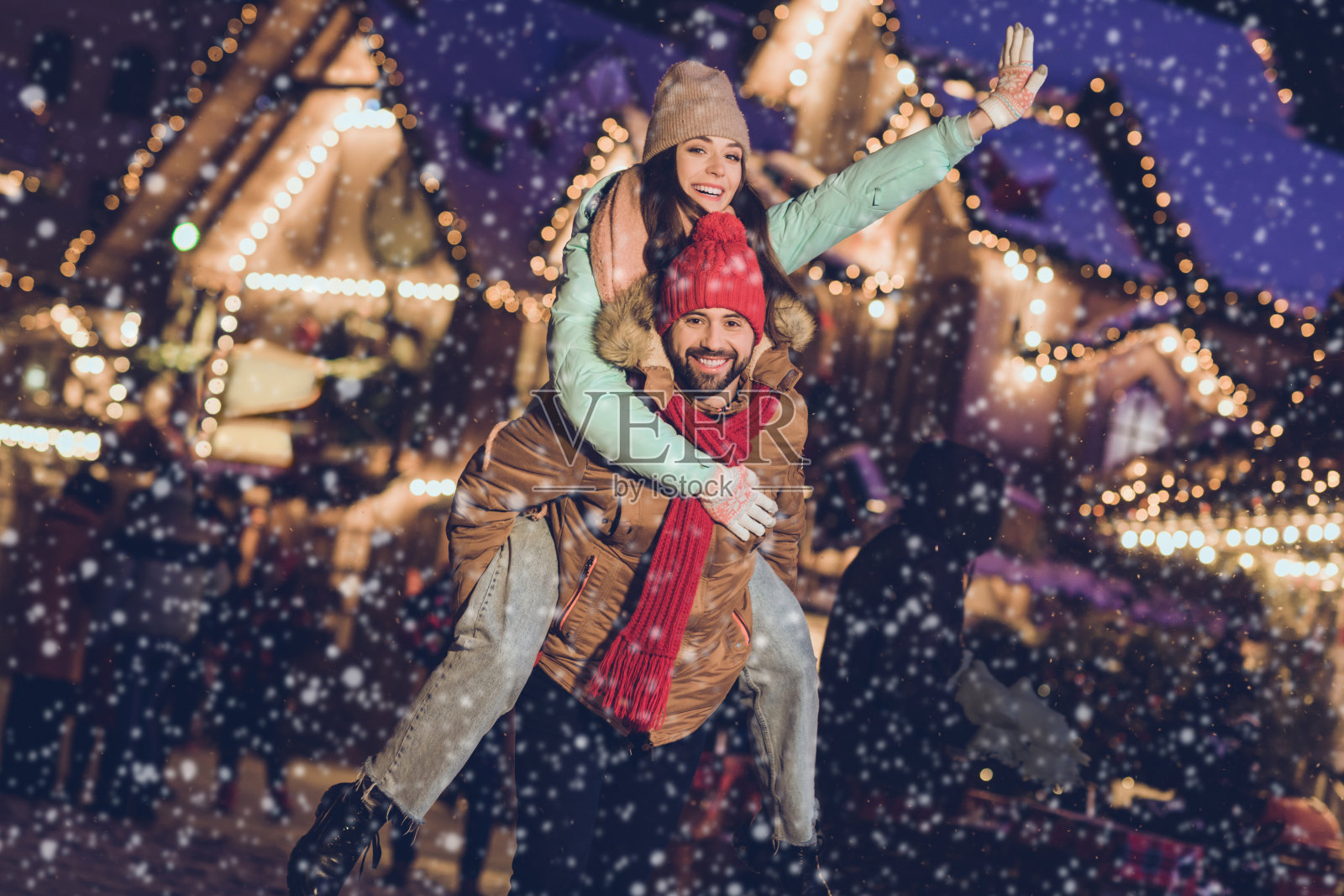 时尚年轻情侣在街头背着对方，穿着帽子、夹克、围巾、手套、牛仔裤和鞋子。照片摄影图片