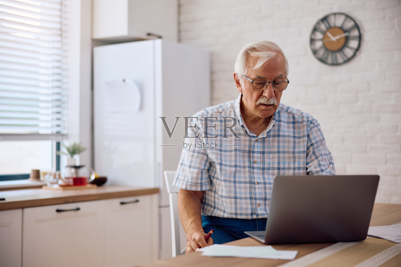 老年男子在家中使用笔记本电脑在线支付账单。照片摄影图片