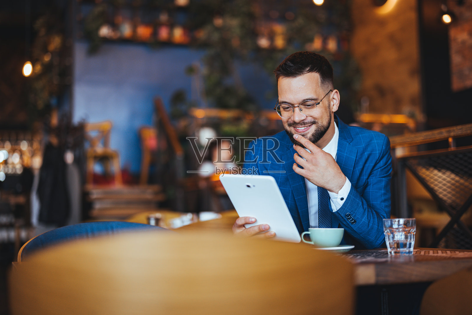 现代咖啡馆环境中使用平板电脑的商务专业人士照片摄影图片