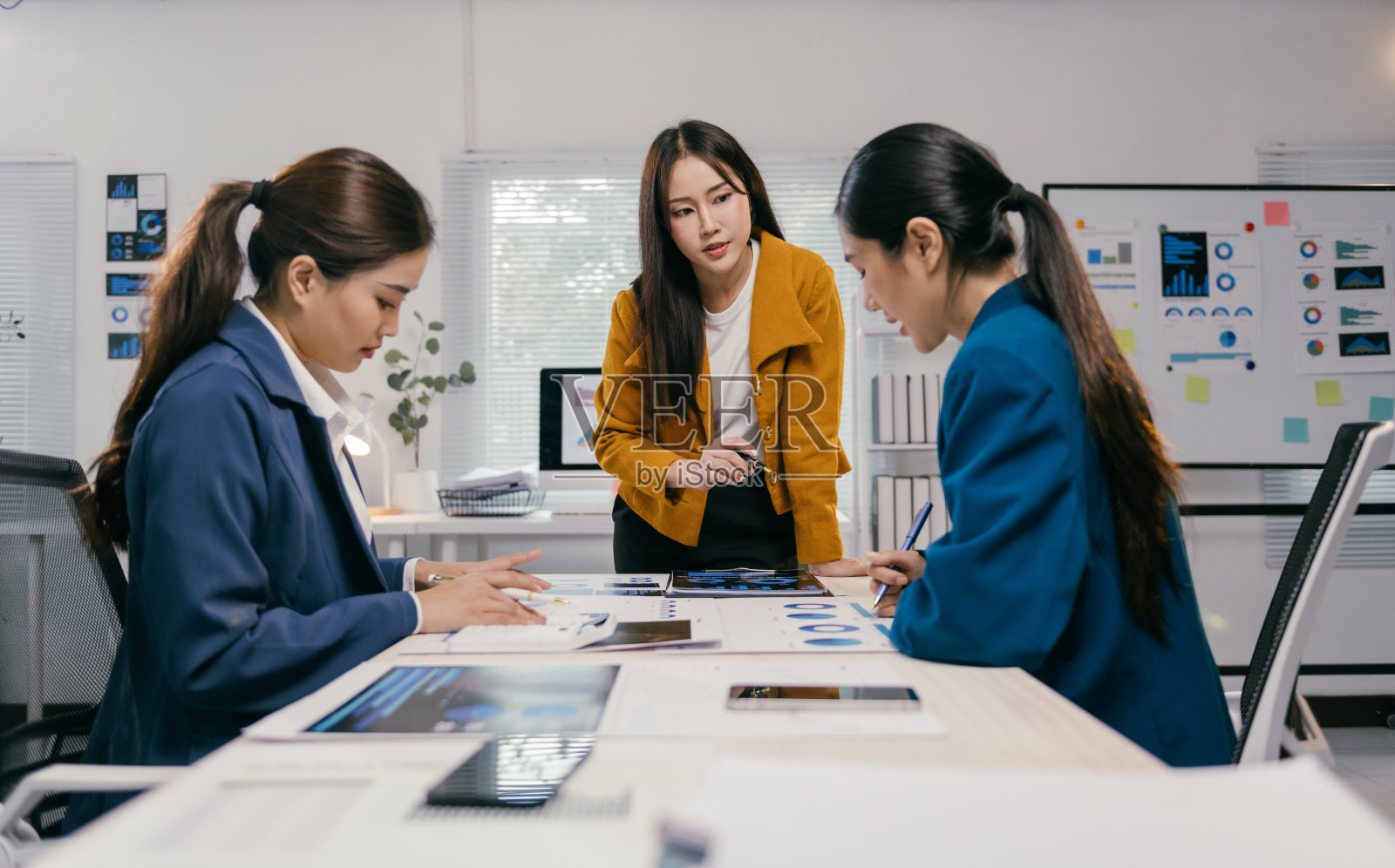 三位亚洲女商人在现代办公室讨论一个新项目，分析图表和数据，共同合作。照片摄影图片