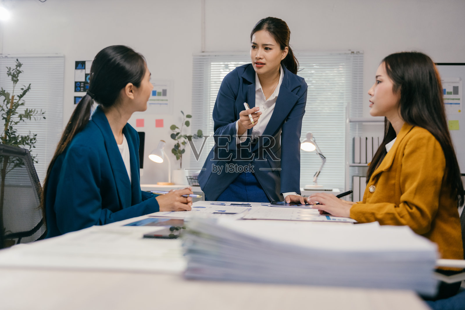 三位亚洲女商人在现代办公室讨论一个项目，分析图表和报告，进行有效的合作。照片摄影图片