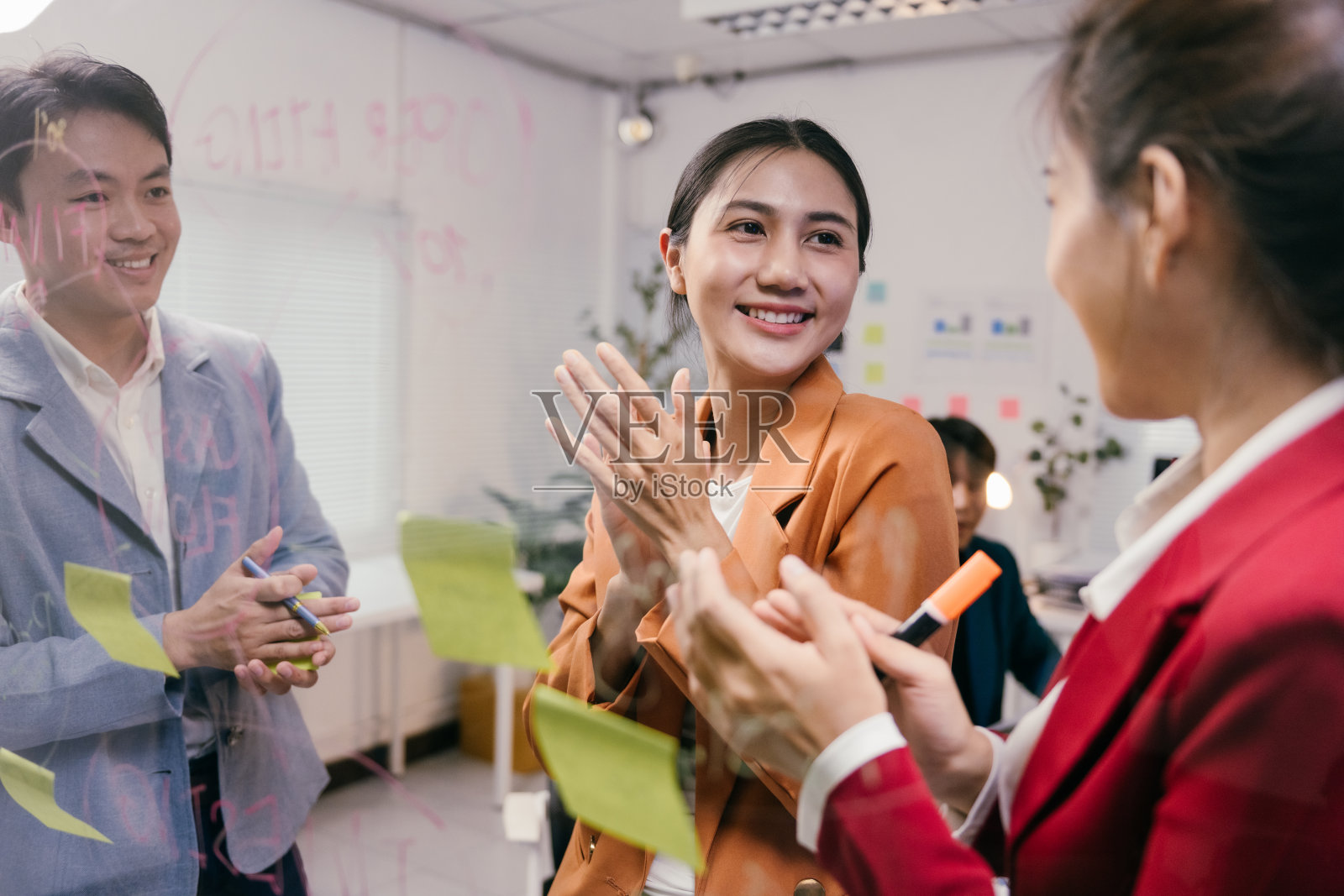 亚洲商务团队在现代办公室的玻璃墙上使用便利贴进行头脑风暴和讨论创意，共同合作一个项目照片摄影图片