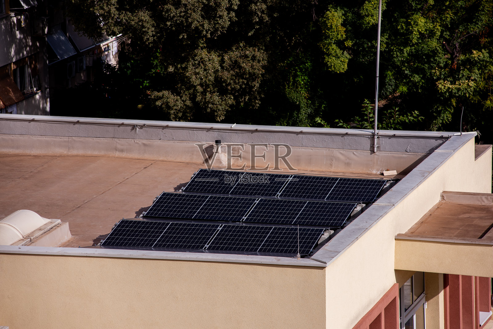带有太阳能电池板和郁郁葱葱树木的公寓大楼照片摄影图片