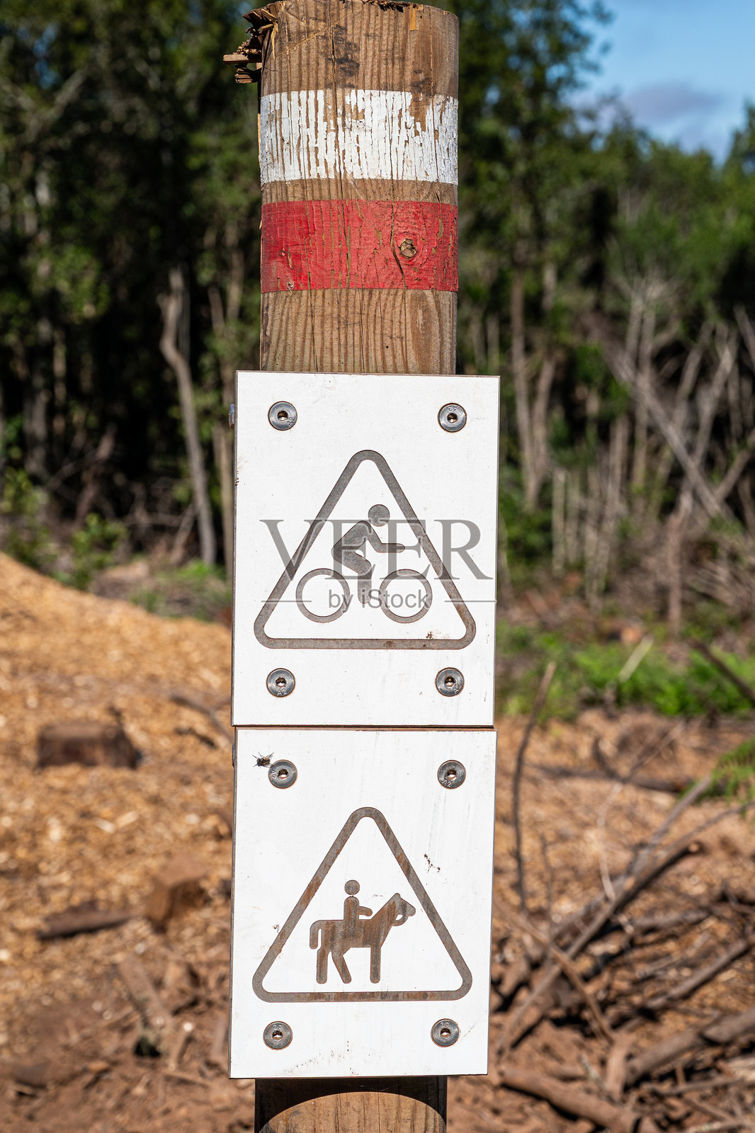 一个红白相间的标志，上面有一个三角形，里面有一个骑自行车和一匹马的人。照片摄影图片