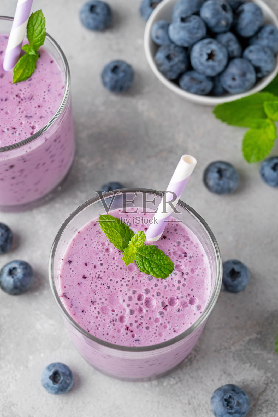 蓝莓、香蕉、奇亚籽和酸奶的冰沙，盛在玻璃杯中，背景为灰色混凝土。健康食品。照片摄影图片