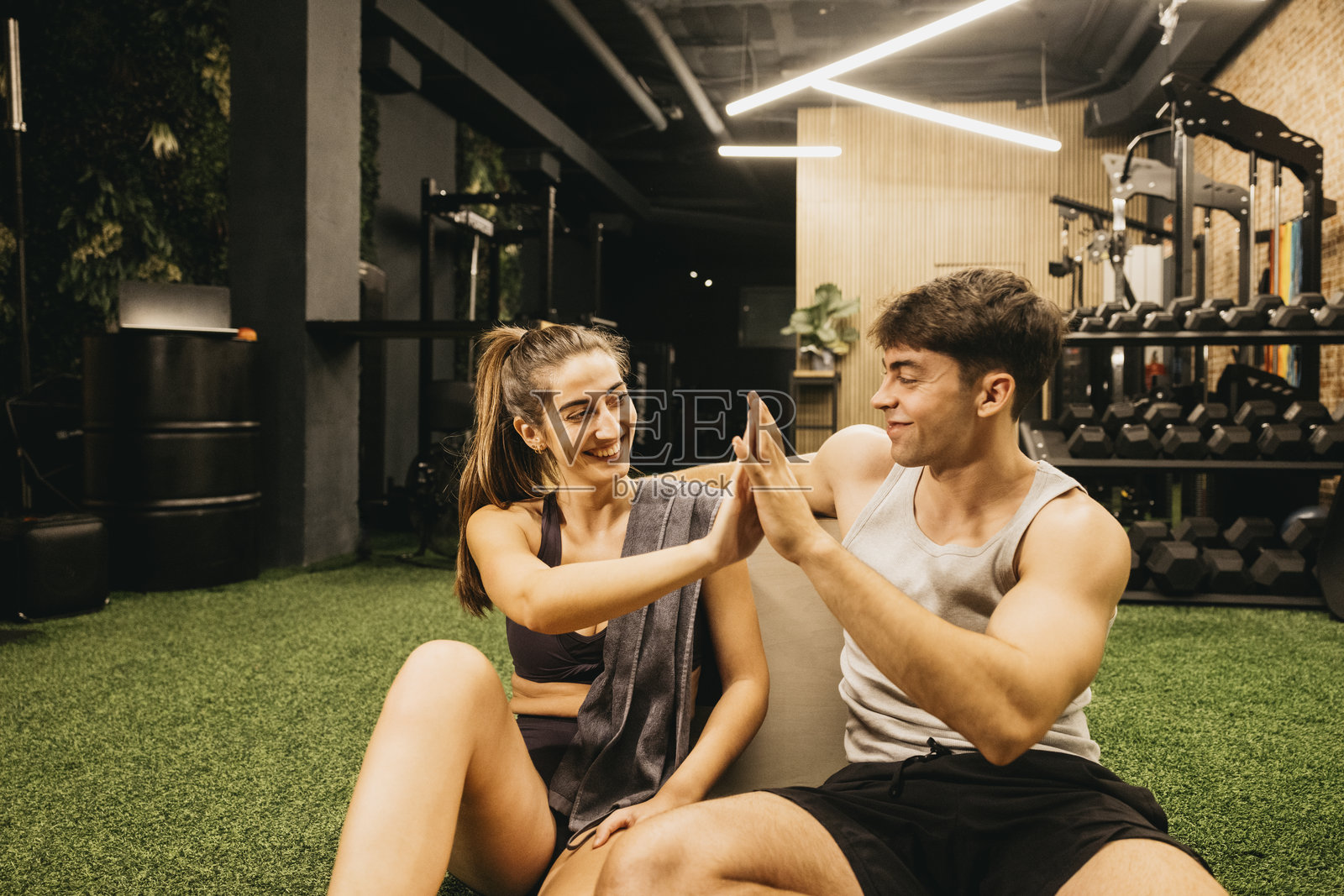 快乐的情侣在健身房庆祝健身成功，击掌相庆照片摄影图片