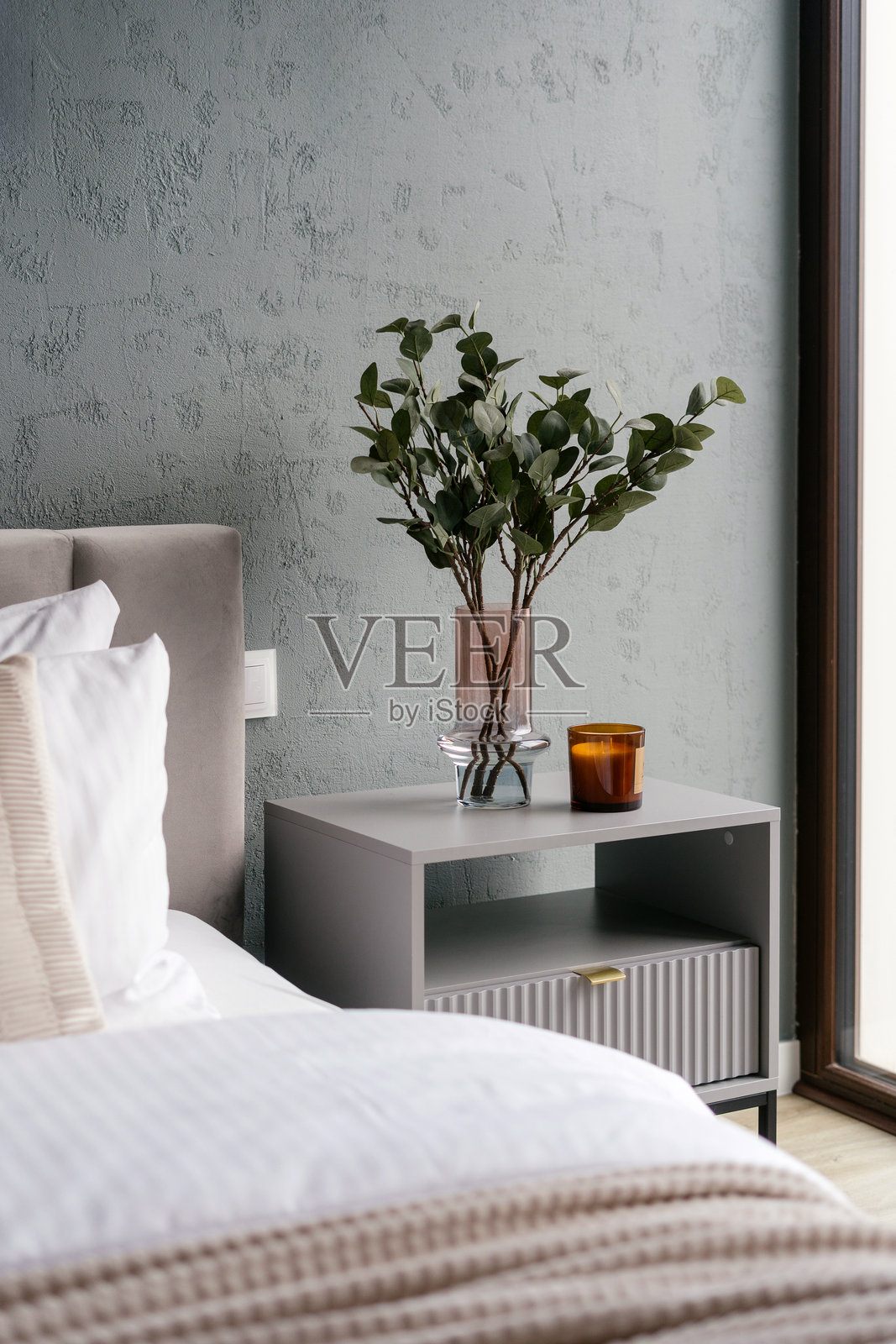 床边桌上摆放着蜡烛和家居装饰，旁边是整理整齐的床铺照片摄影图片