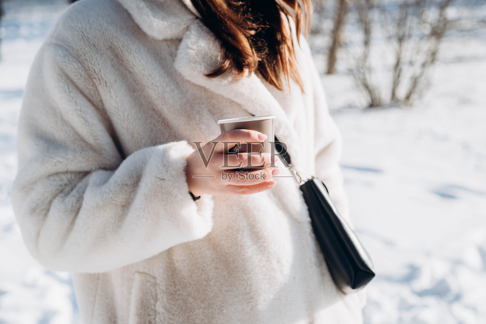 冬季森林中，女性手中拿着一杯热饮的纸杯。照片摄影图片