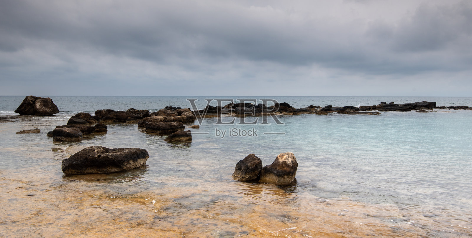 碧绿色的海水在阴天冲刷着岩石，宁静的氛围照片摄影图片