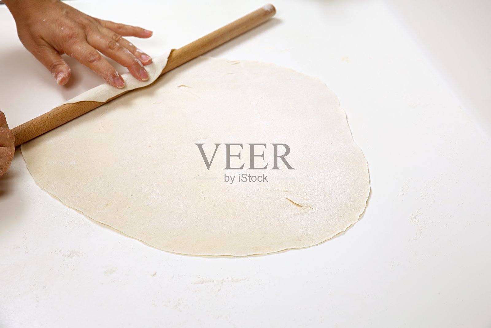 一位女性正在用擀面杖擀制菠菜饺子的面团照片摄影图片