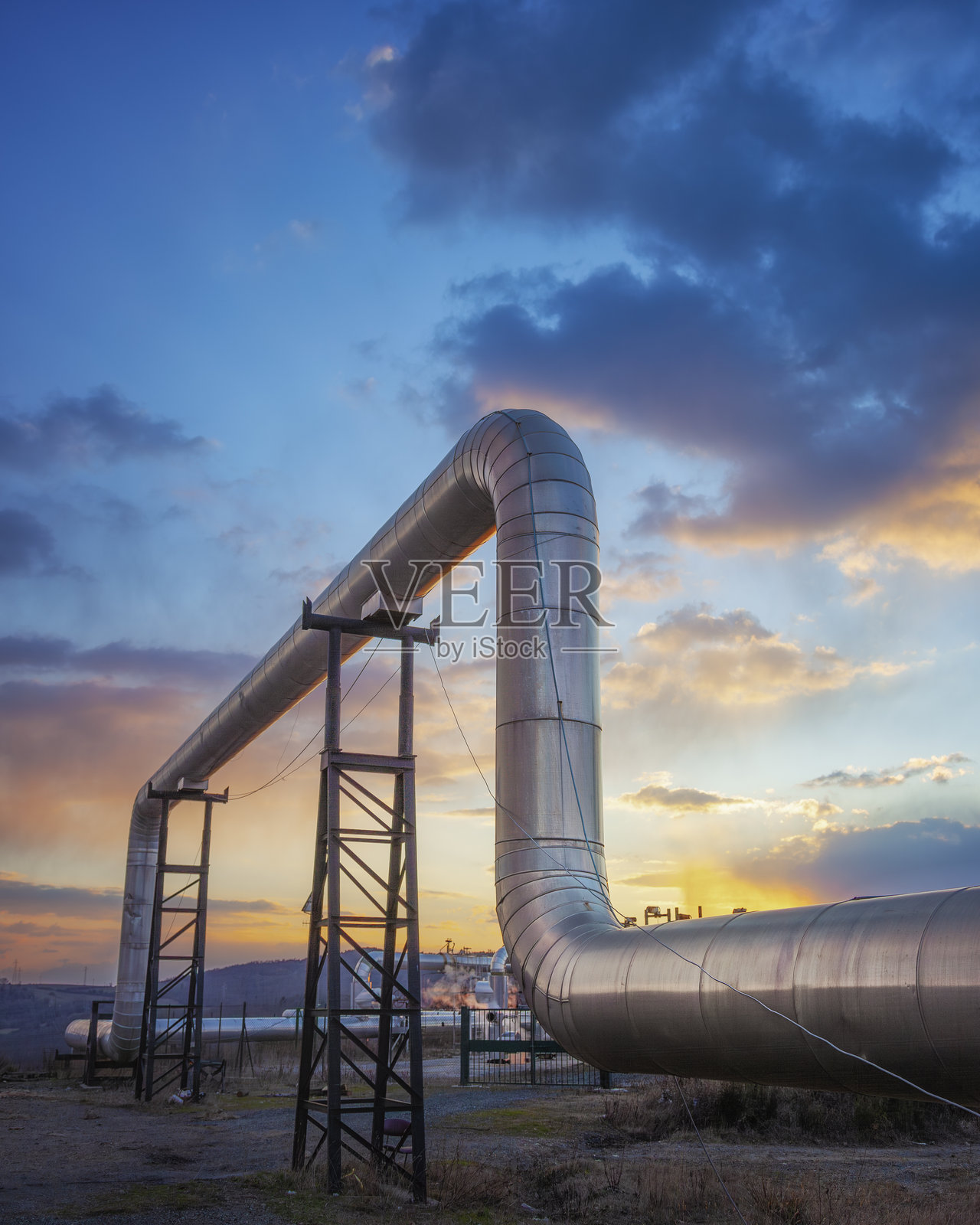 地热能。意大利托斯卡纳地区拉尔德雷洛的工厂管道在日落时分。照片摄影图片