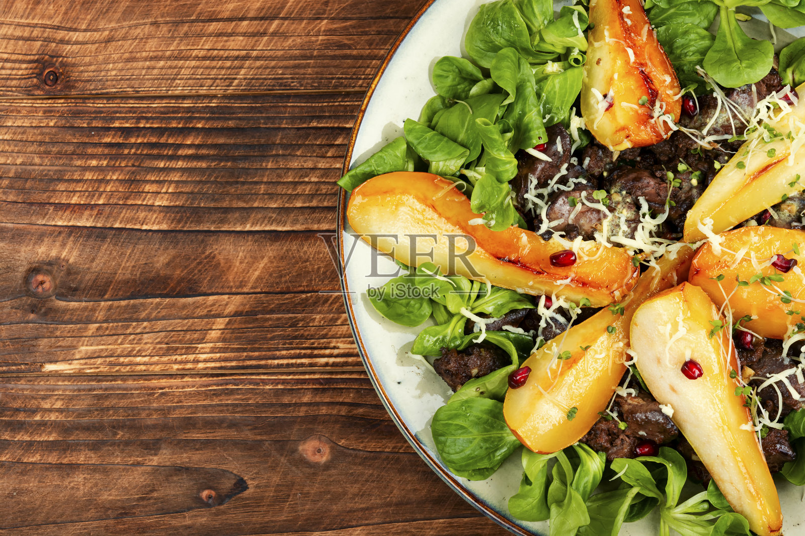 木桌上的盘子里的沙拉。照片摄影图片