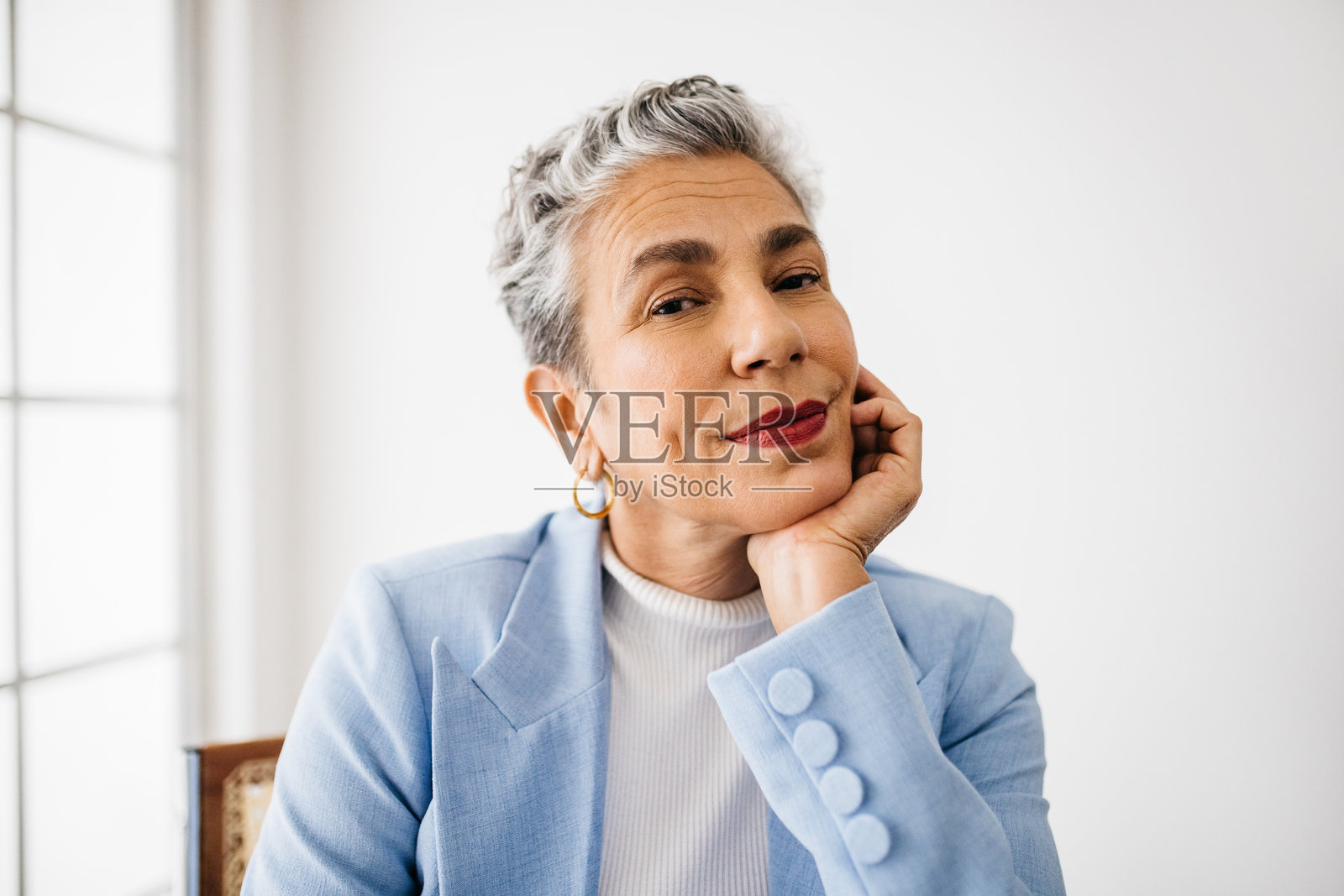 自信的资深商务女性坐在办公室里，穿着优雅的商务装照片摄影图片