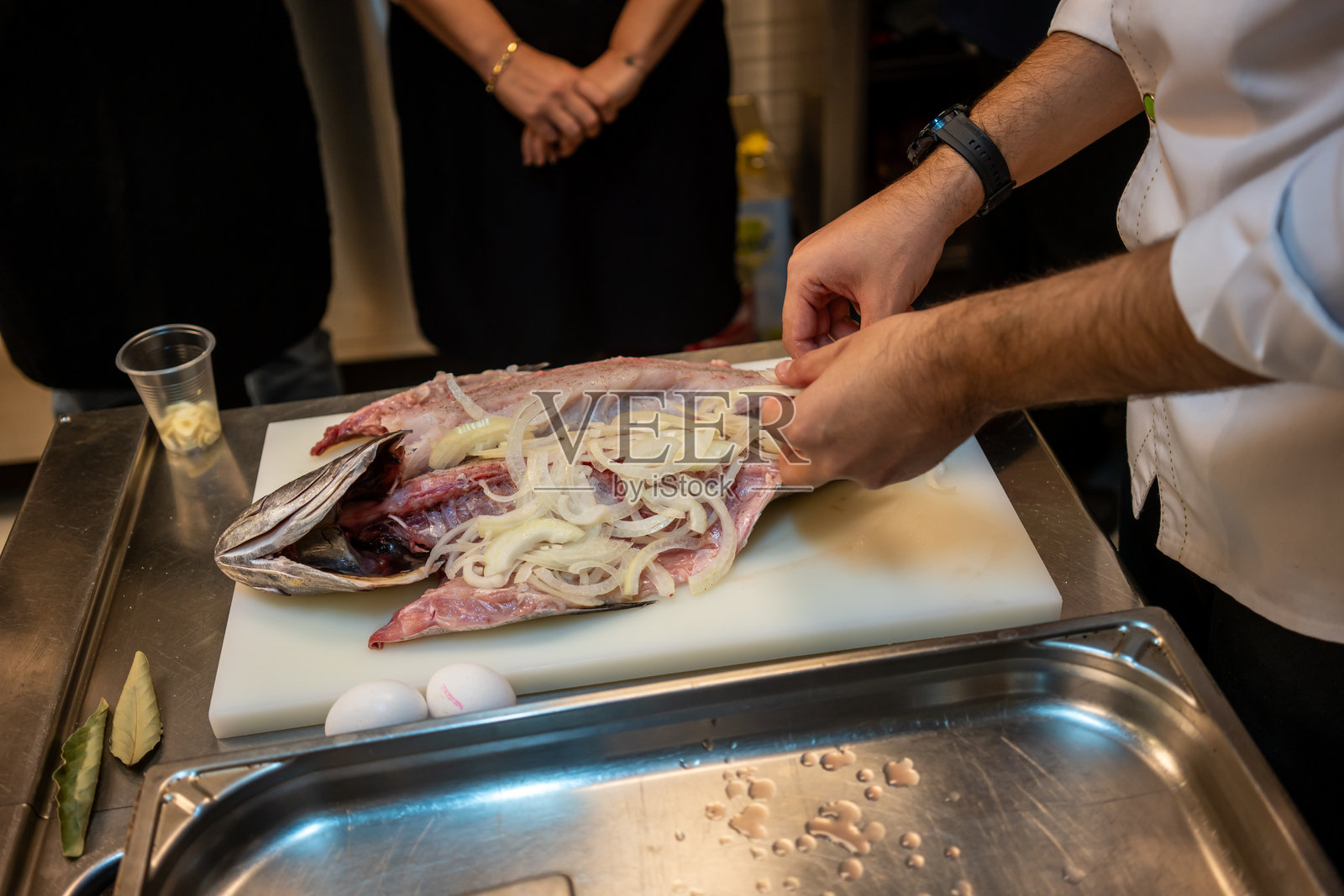 男性手将洋葱放入生鲑鱼中，准备烹饪的静物画面照片摄影图片