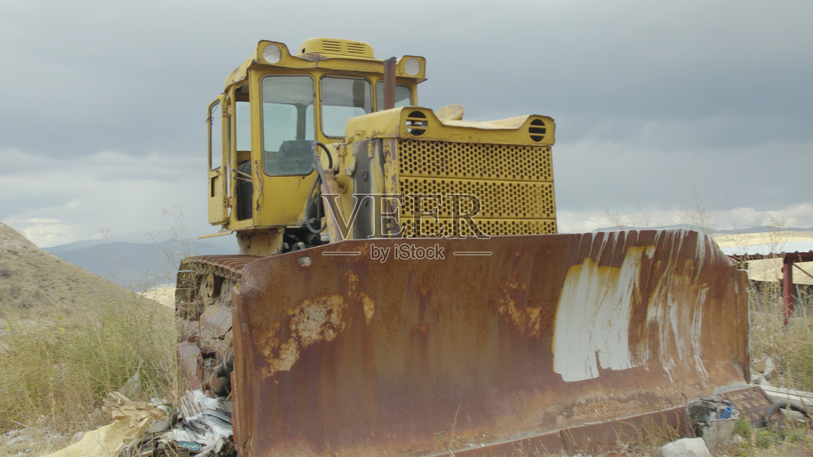 被遗弃的生锈拖拉机在山谷风景中。破旧的黄色生锈拖拉机在风景如画的山谷中。被遗弃的黄色拖拉机，破损且生锈，位于乡村山谷。风化的黄色拖拉机，破损且生锈，位于山谷中。旧的黄色破损农用拖拉机。照片摄影图片