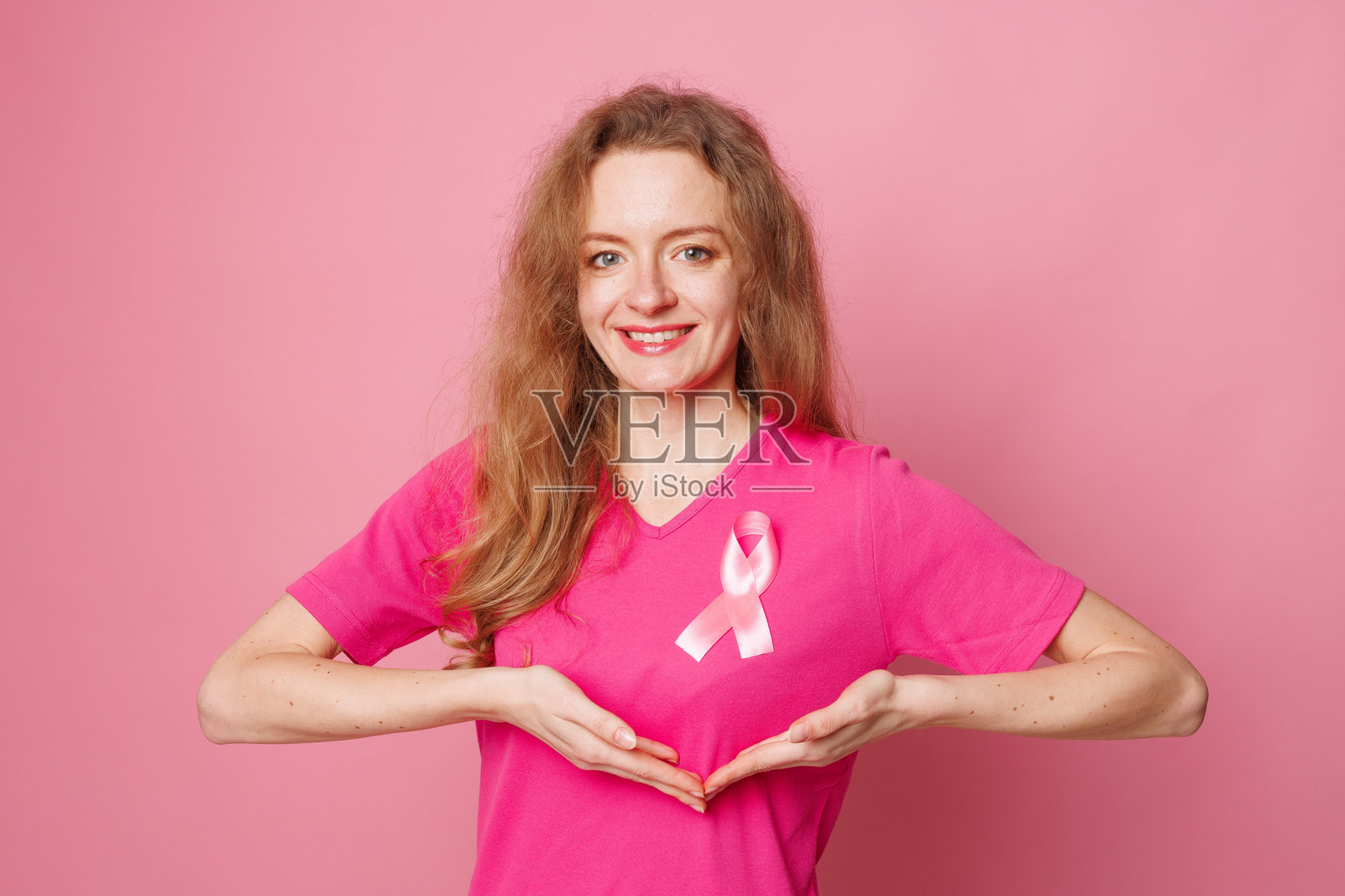 微笑的年轻女性特写，手持象征乳腺癌意识的粉色丝带照片摄影图片